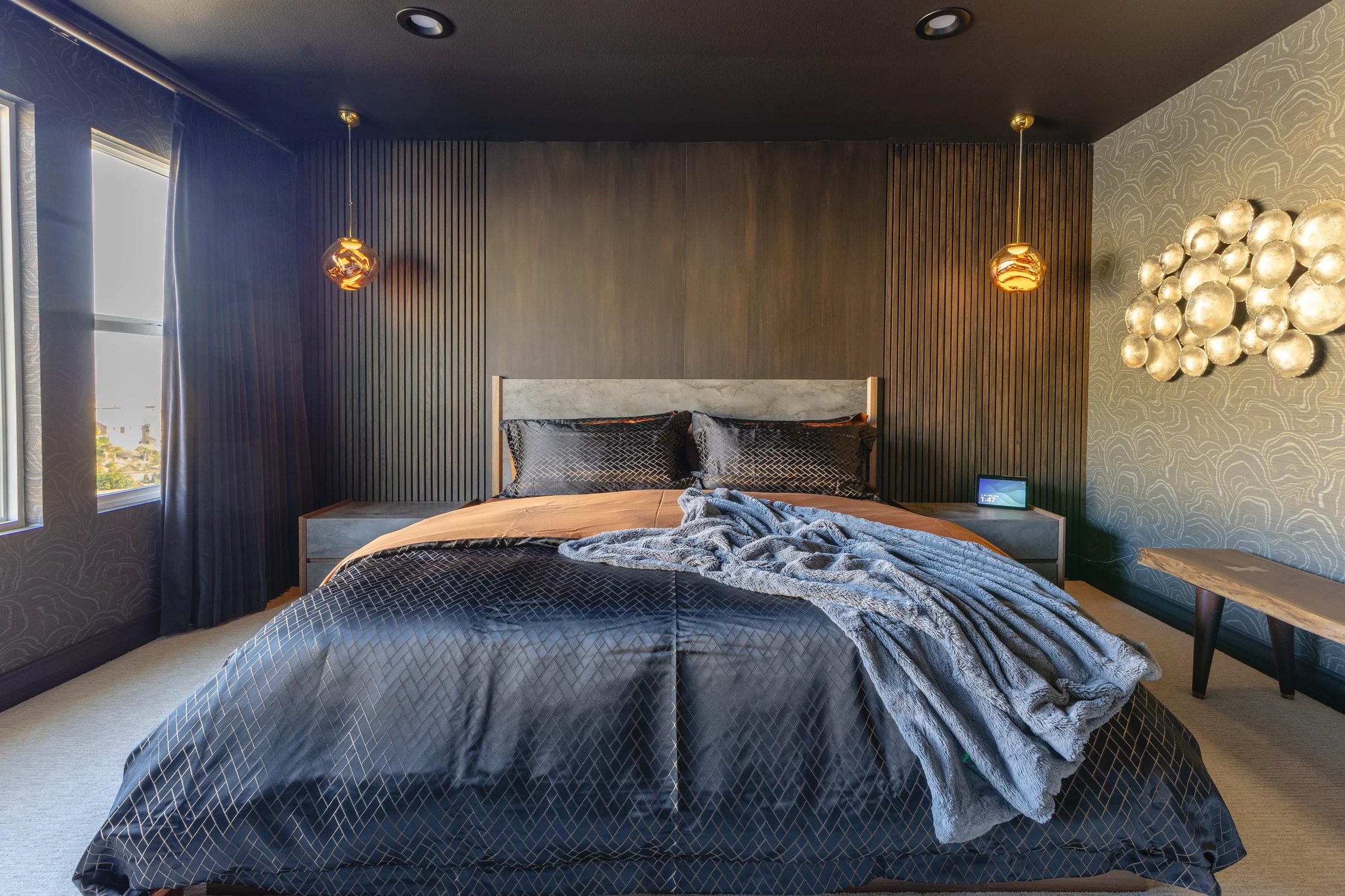 Dark bedroom with paneled headboard wall and metallic sculpture