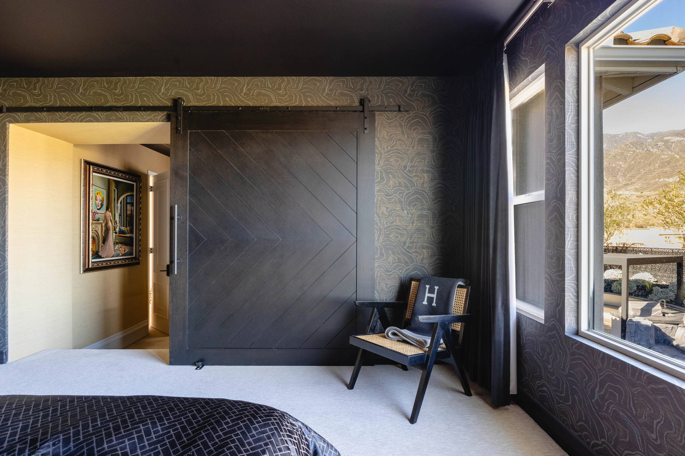 Dark bedroom with sliding wood door and window-side chair