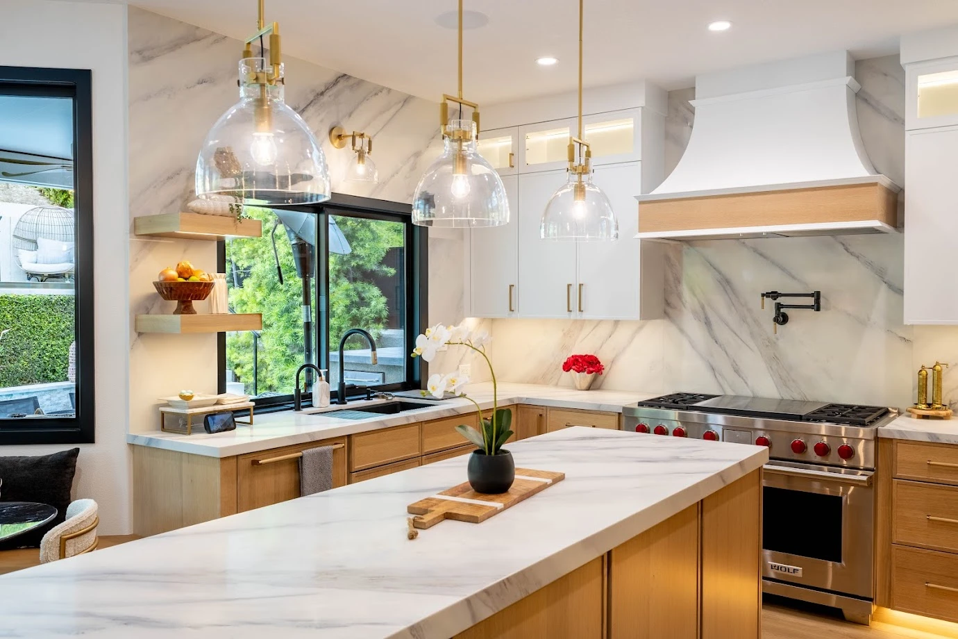 Kitchen with marble island, white hood, and glass pendant lights