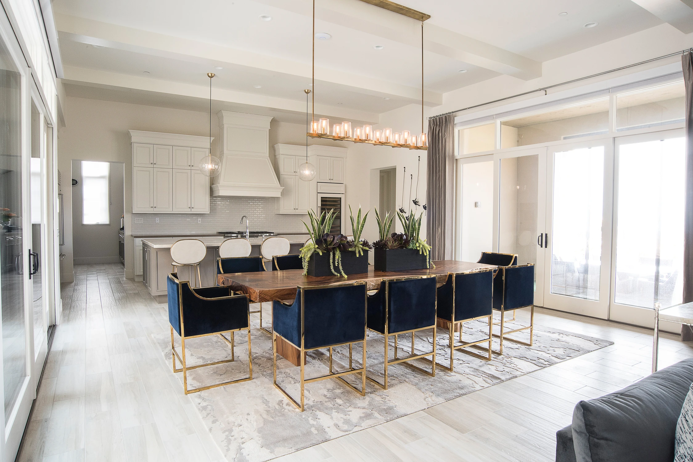 Open kitchen and dining room with navy chairs and long brass pendant