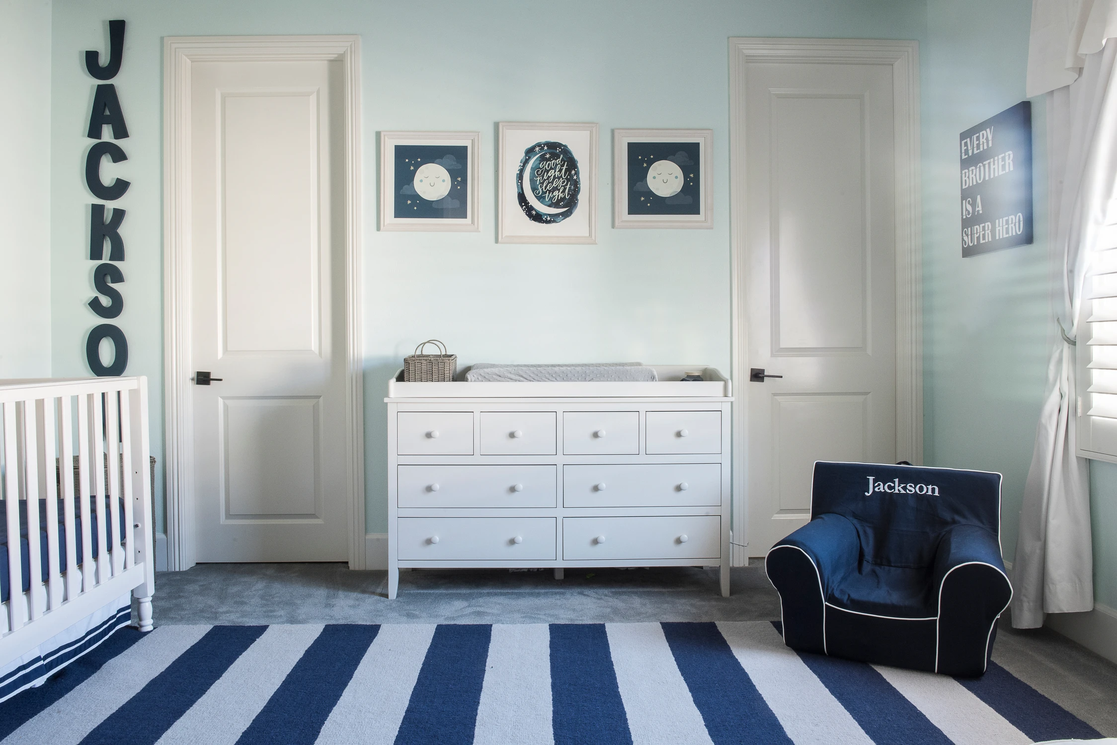 Nursery dresser wall with navy striped rug and framed art
