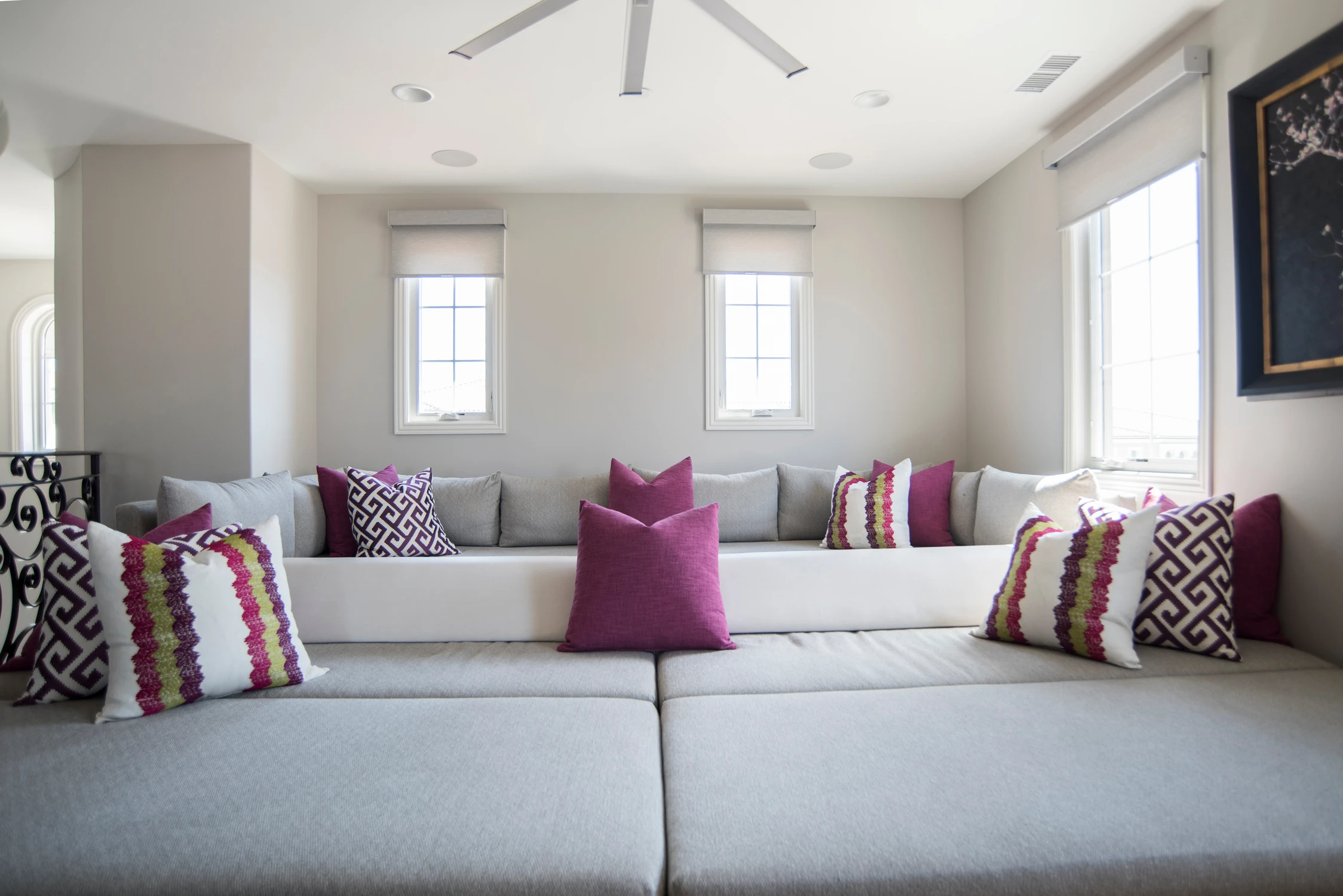 Upper sitting room with pale sectional and patterned magenta pillows