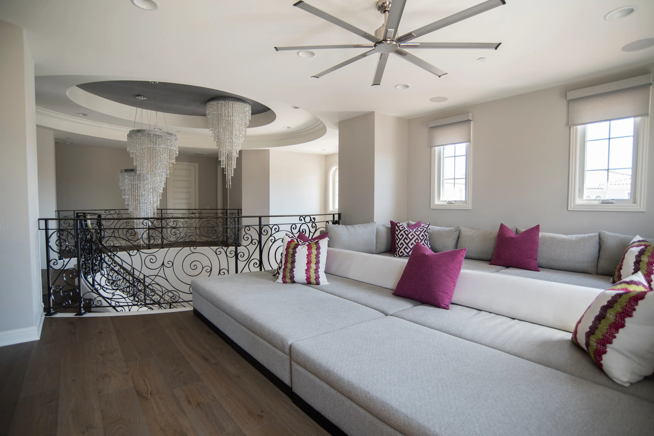 Upper sitting room with pale sectional and chandelier beyond the railing