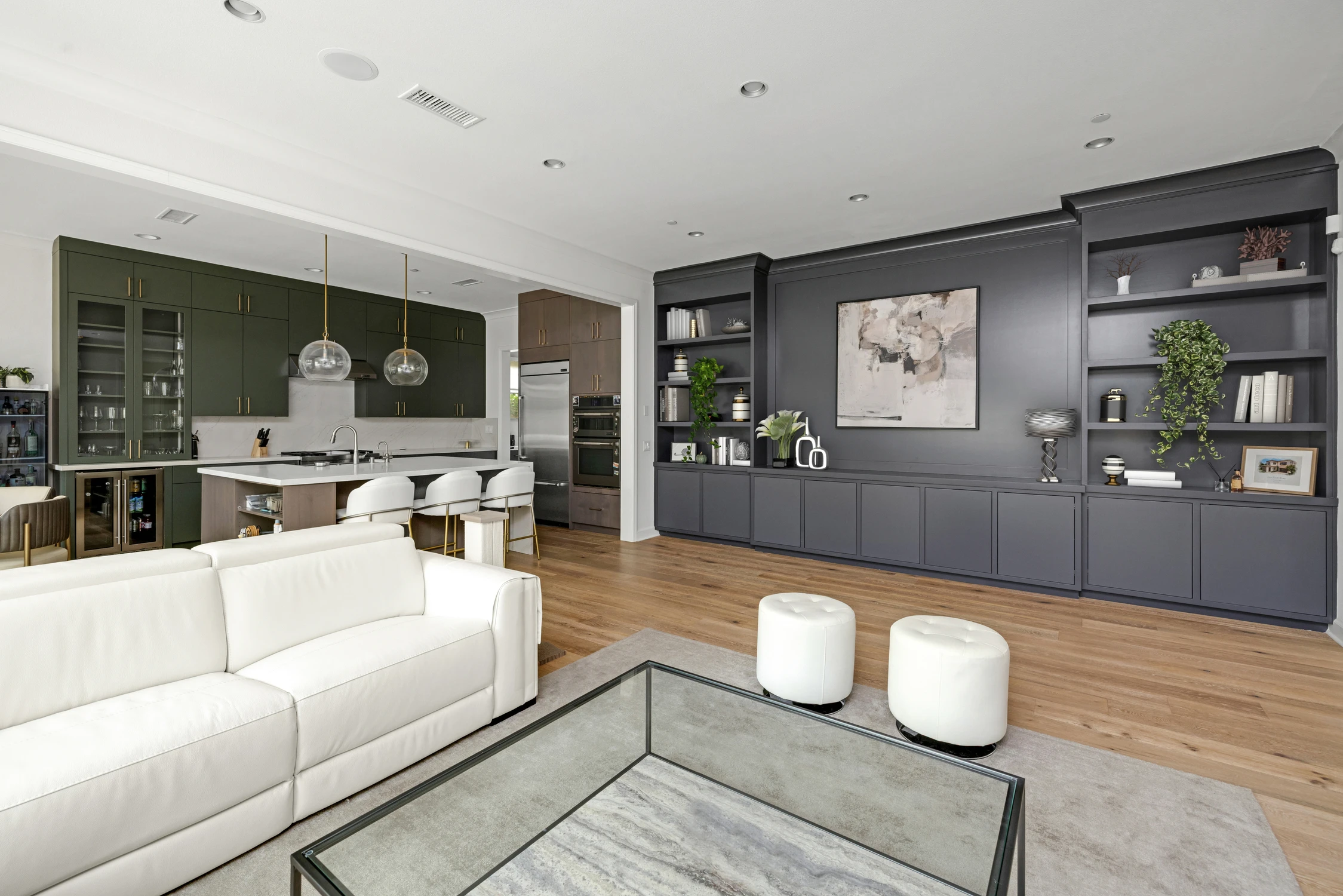 Open living area with white sectional, green kitchen, and dark built-in wall