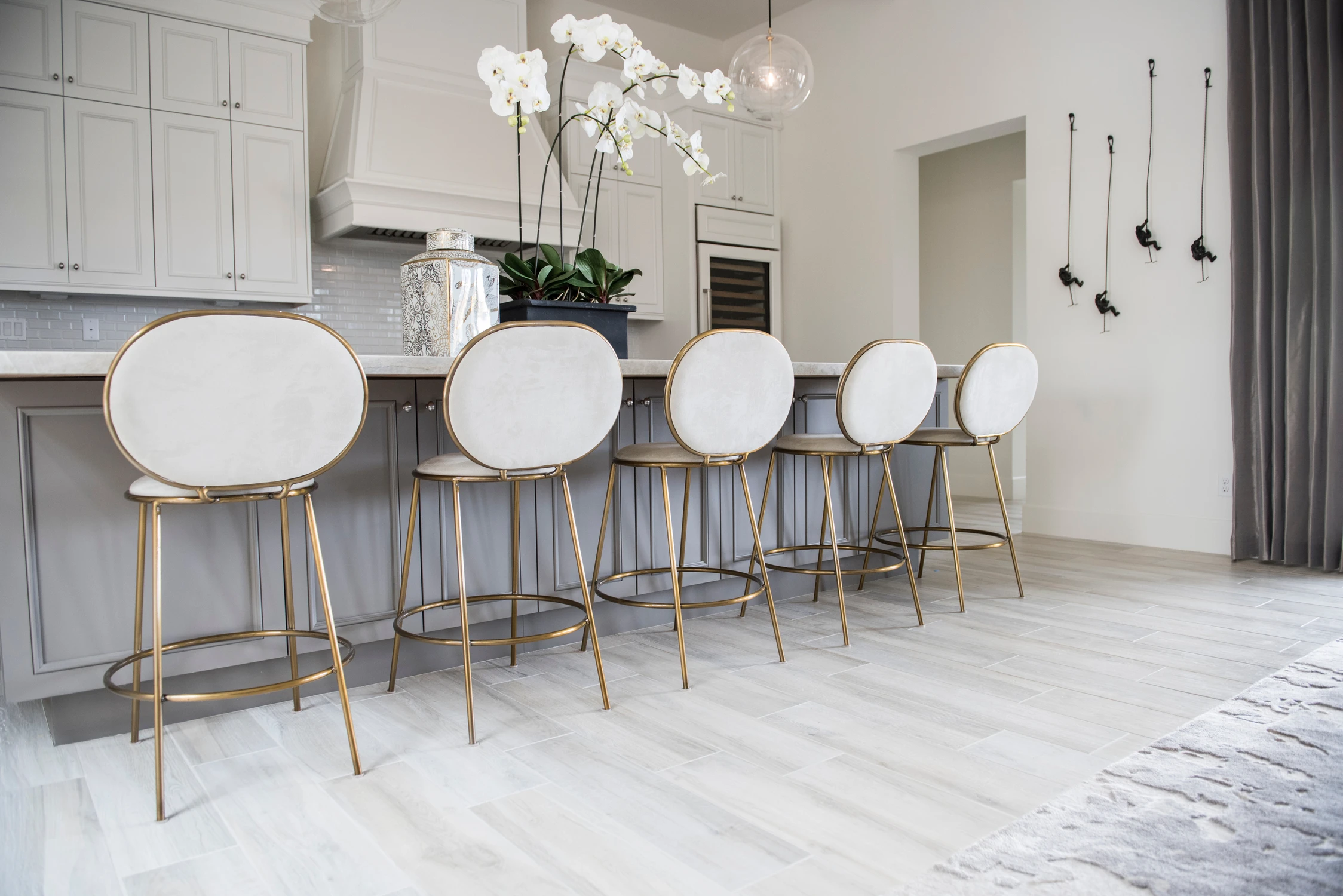 White kitchen island with white stools and orchid arrangement