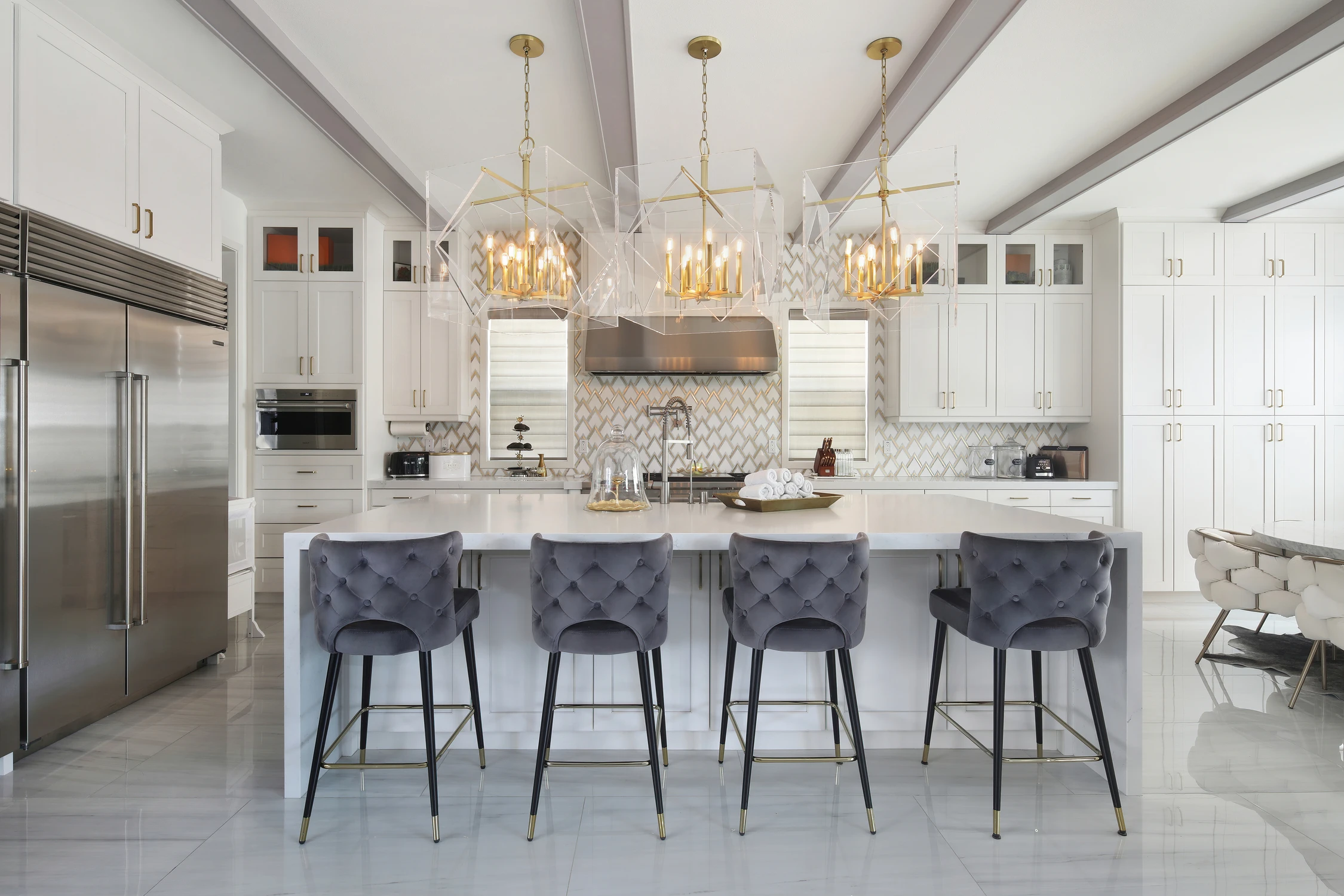 White kitchen island with dark stools and glass pendant lights
