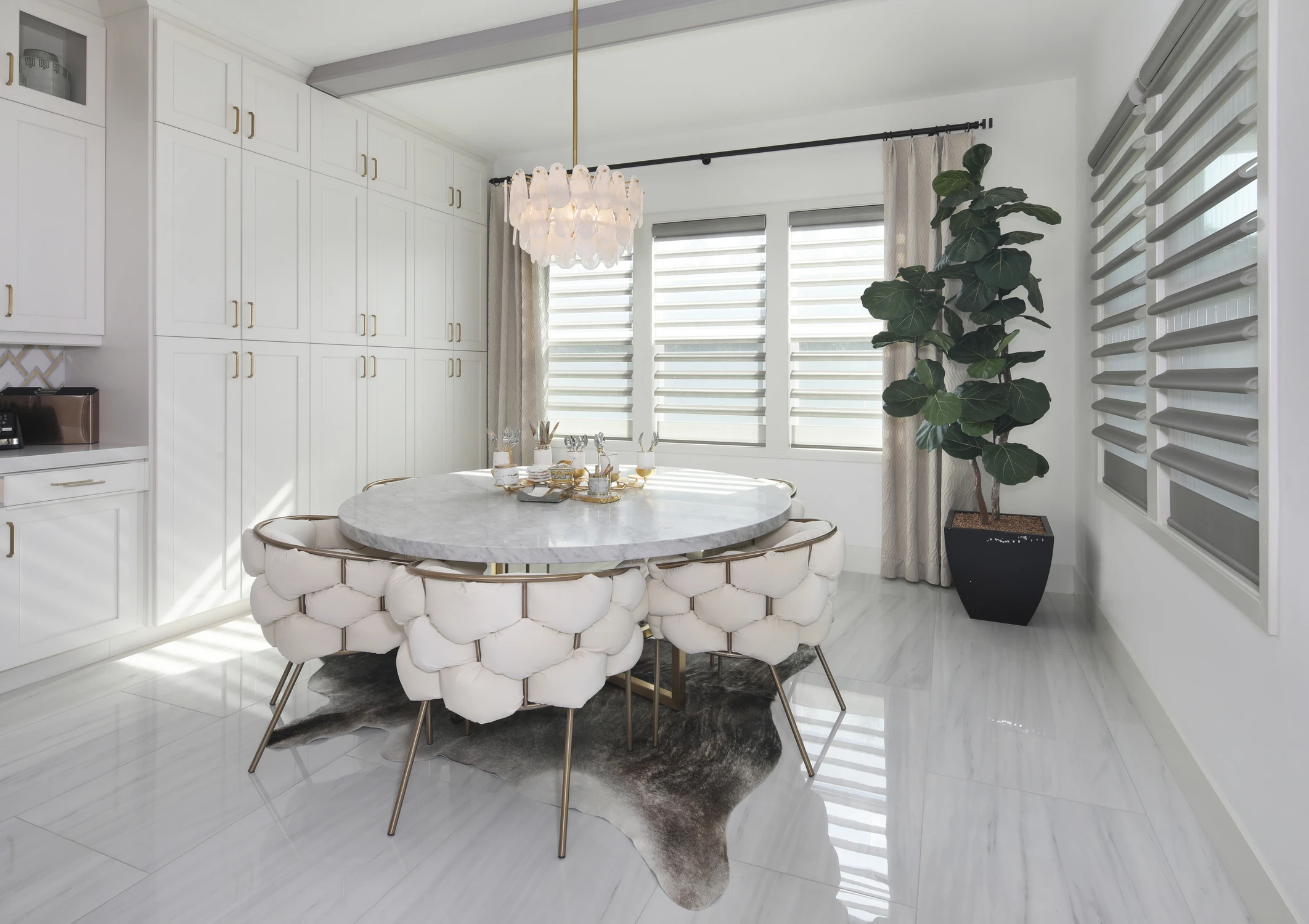 Breakfast nook with round table, white chairs, and shuttered windows