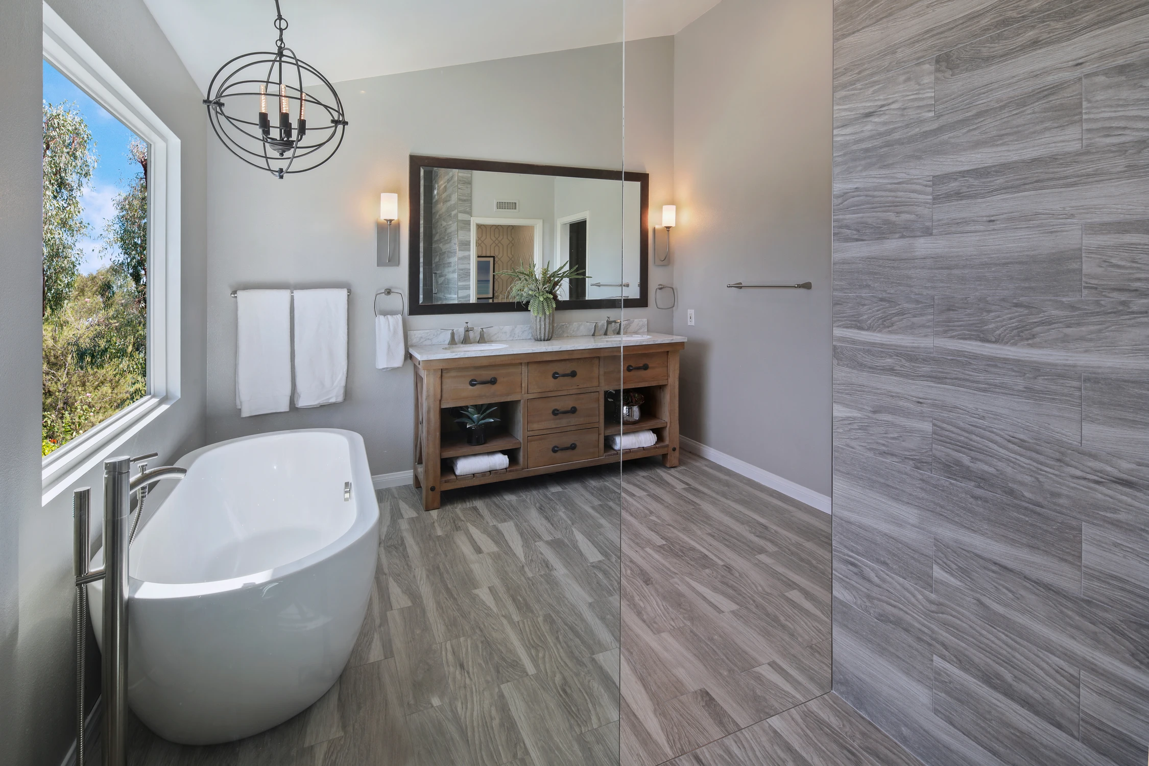Master bathroom with freestanding tub beside a large wooded window