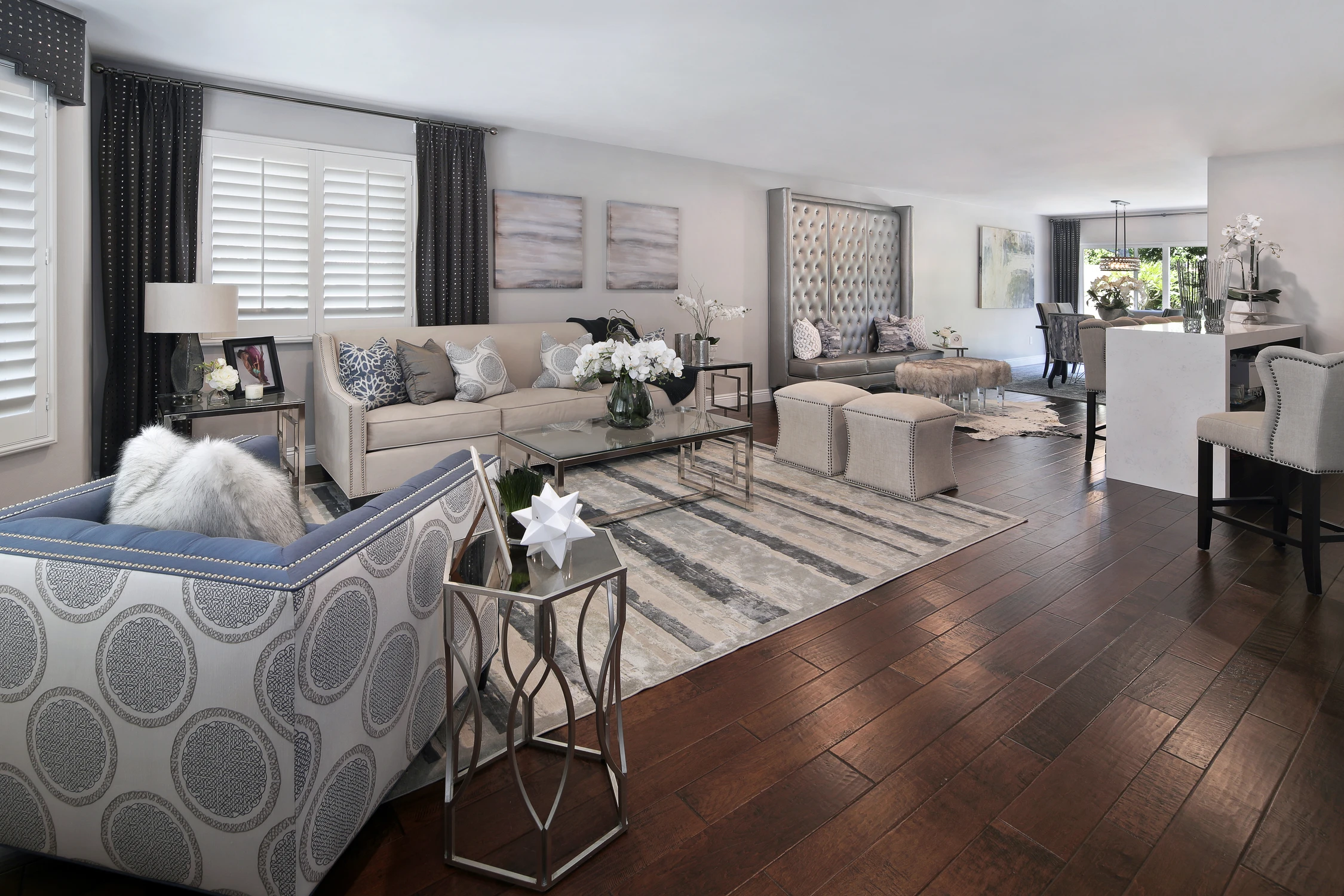 Open living room with tufted bench seating, dark wood floor, and long bar
