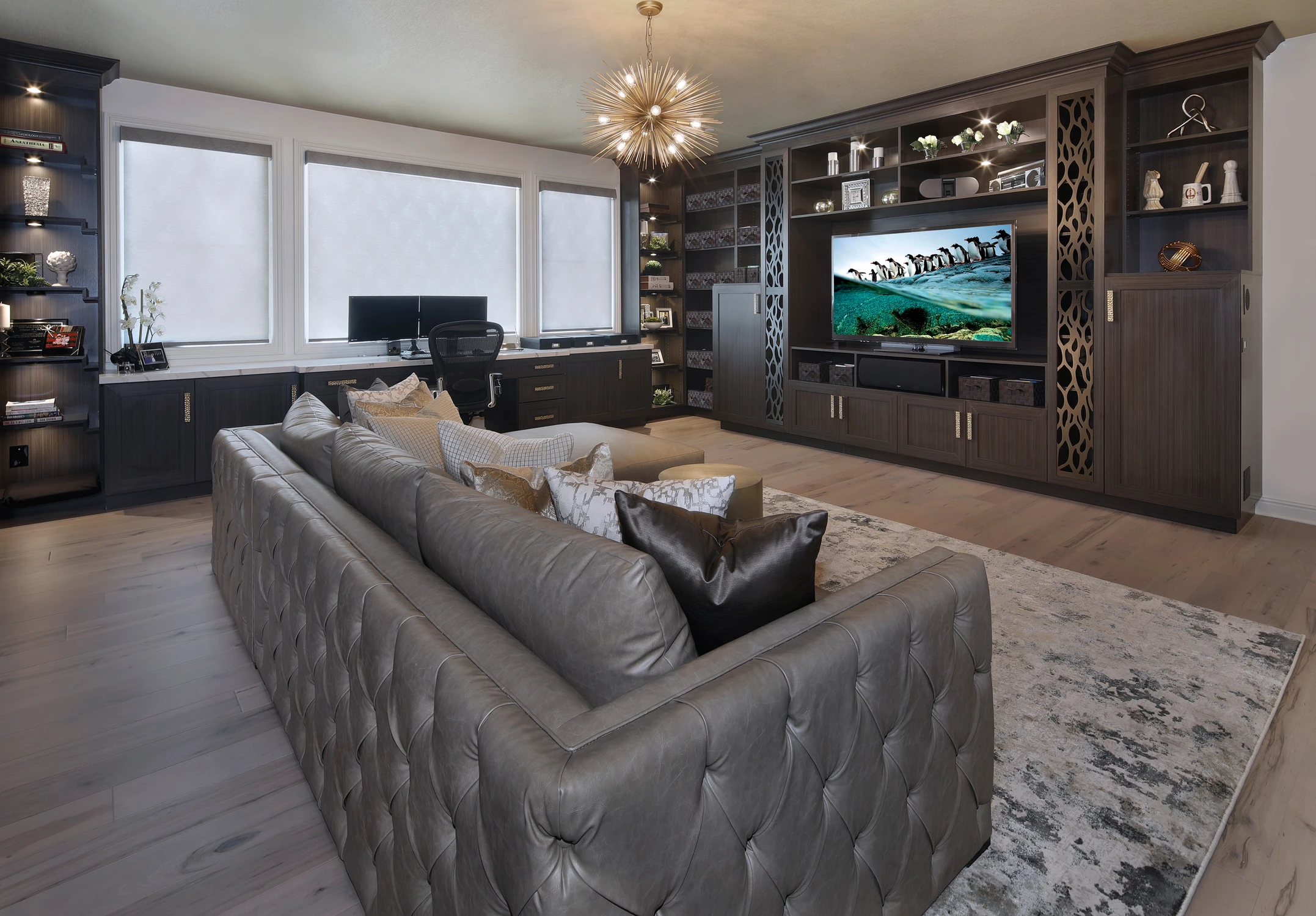 Home office with dark built-ins, sectional seating, and window desk