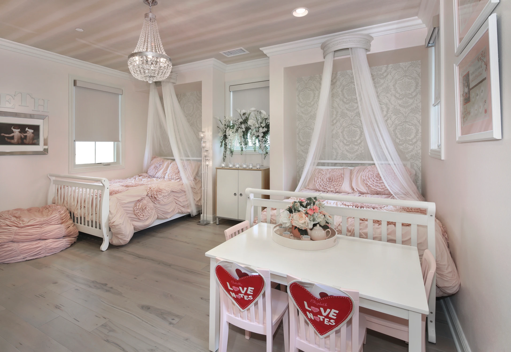 Pink nursery with canopy beds, cribs, and a children's table