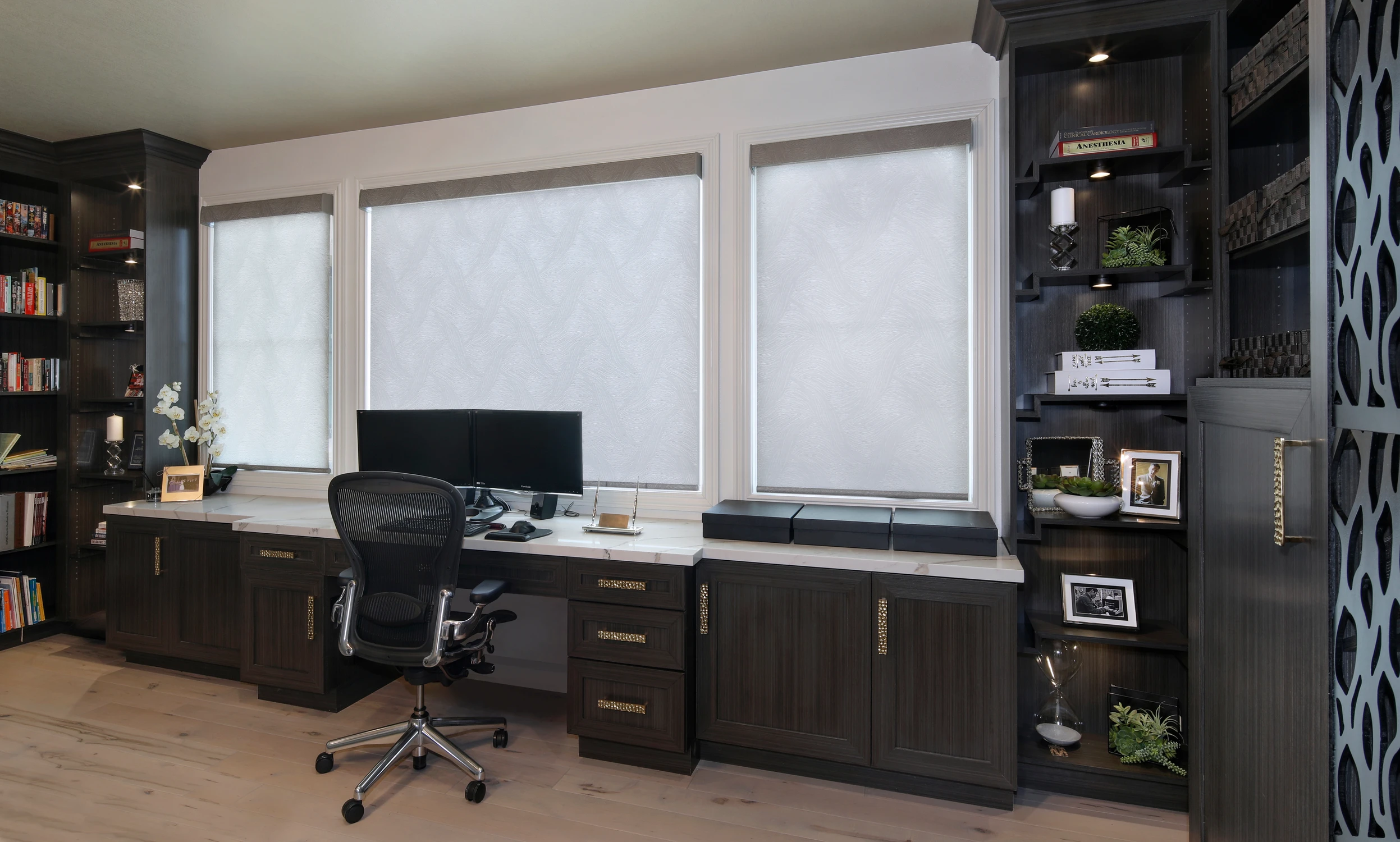 Home office desk framed by dark shelving and patterned panels