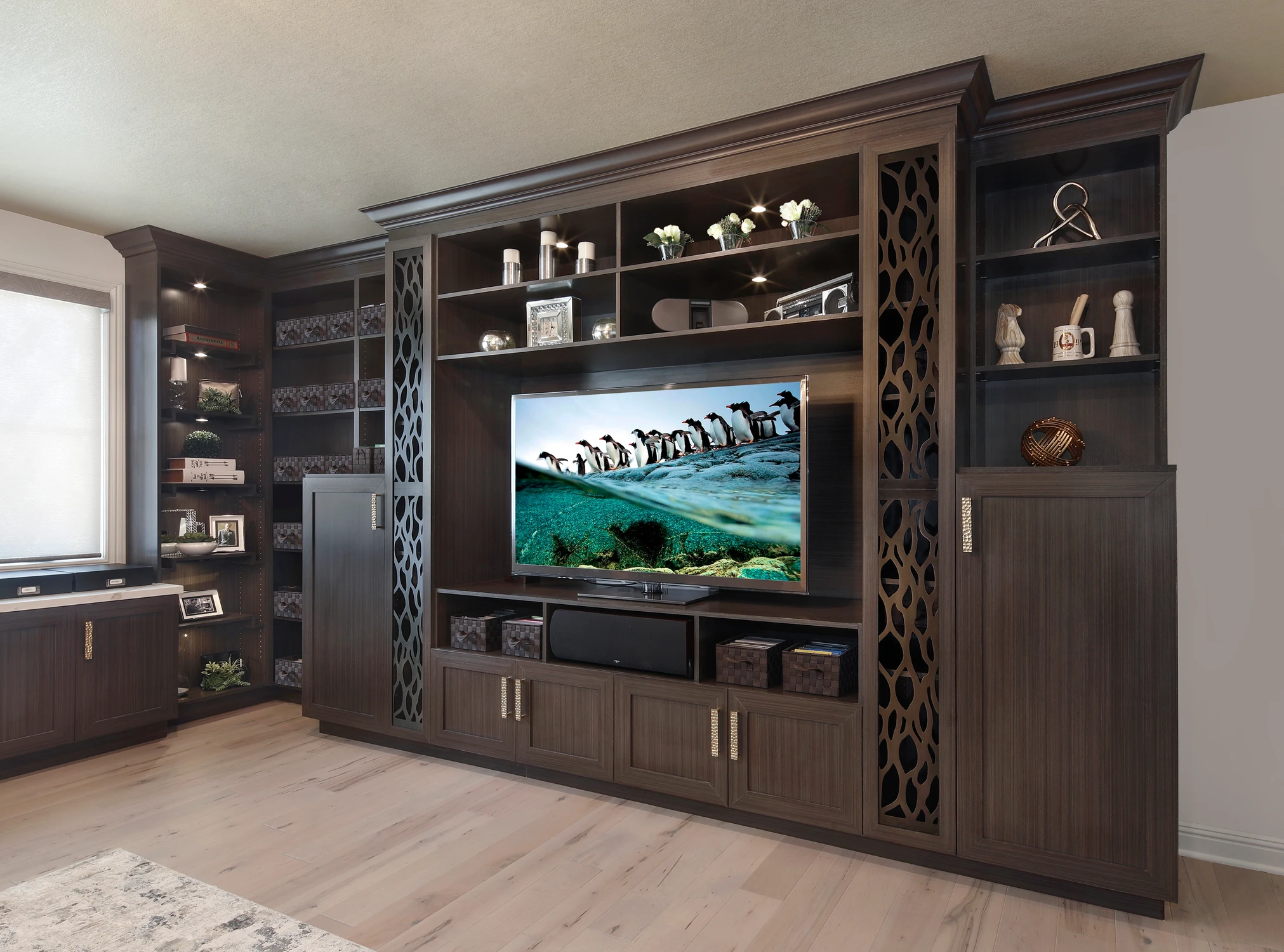 Dark wood built-in with television, shelving, and concealed storage