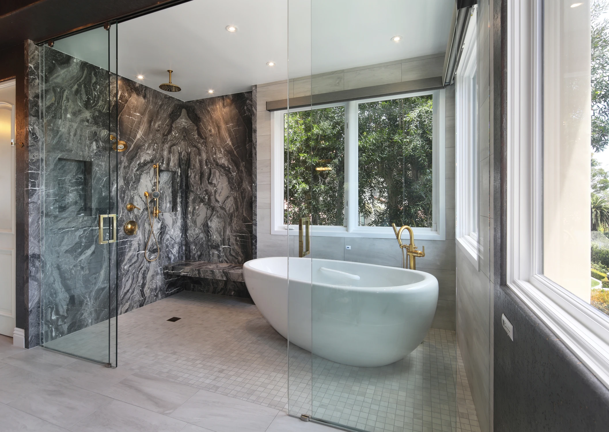 Bathroom with freestanding tub, dark stone shower, and brass fixtures