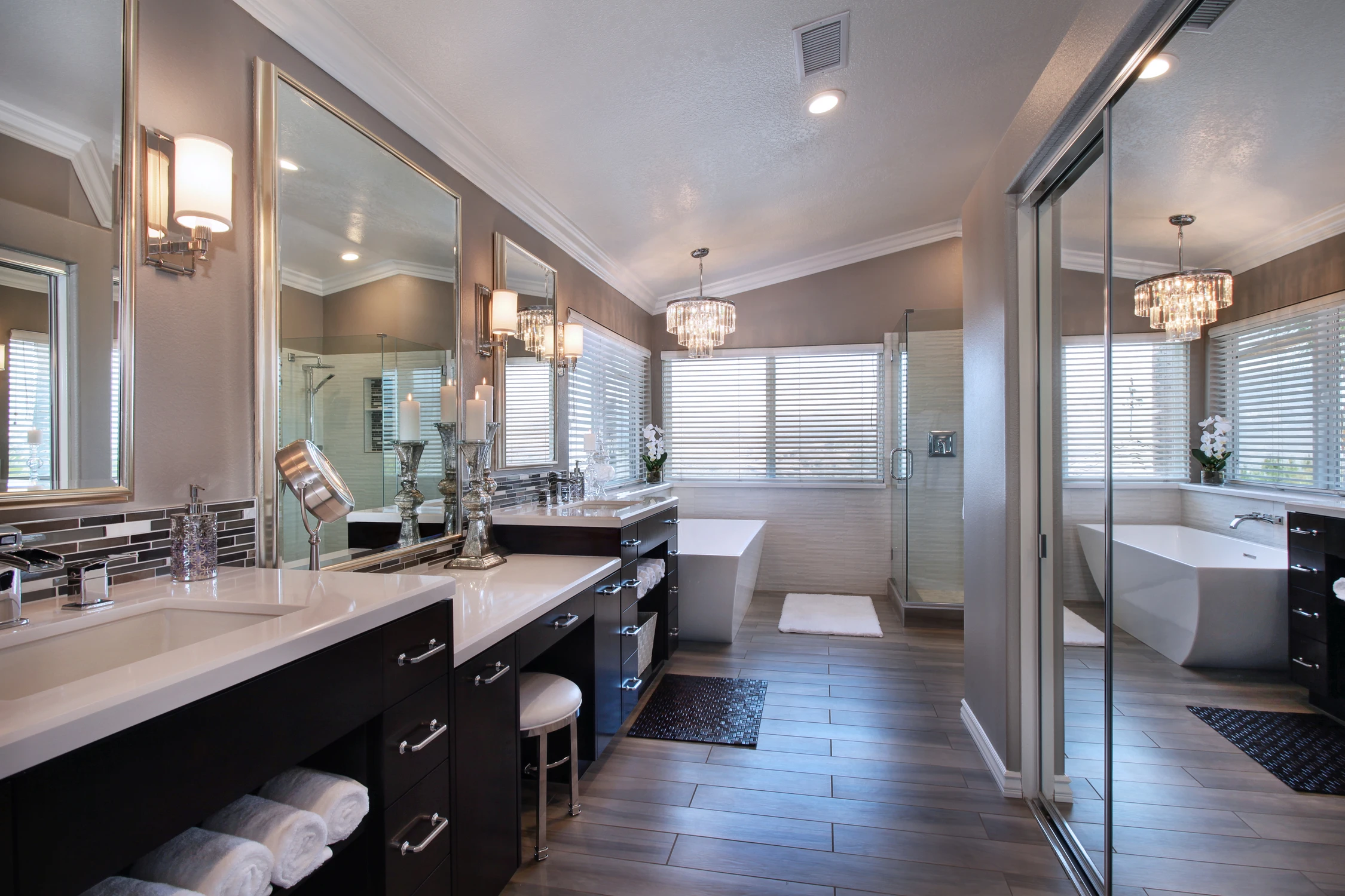 Bathroom vanity with dark drawers, white countertop, and wall mirrors