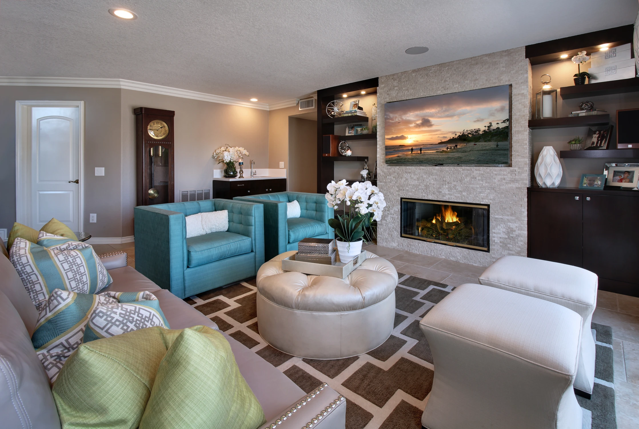 Living room with teal seating, dark built-ins, and stone fireplace