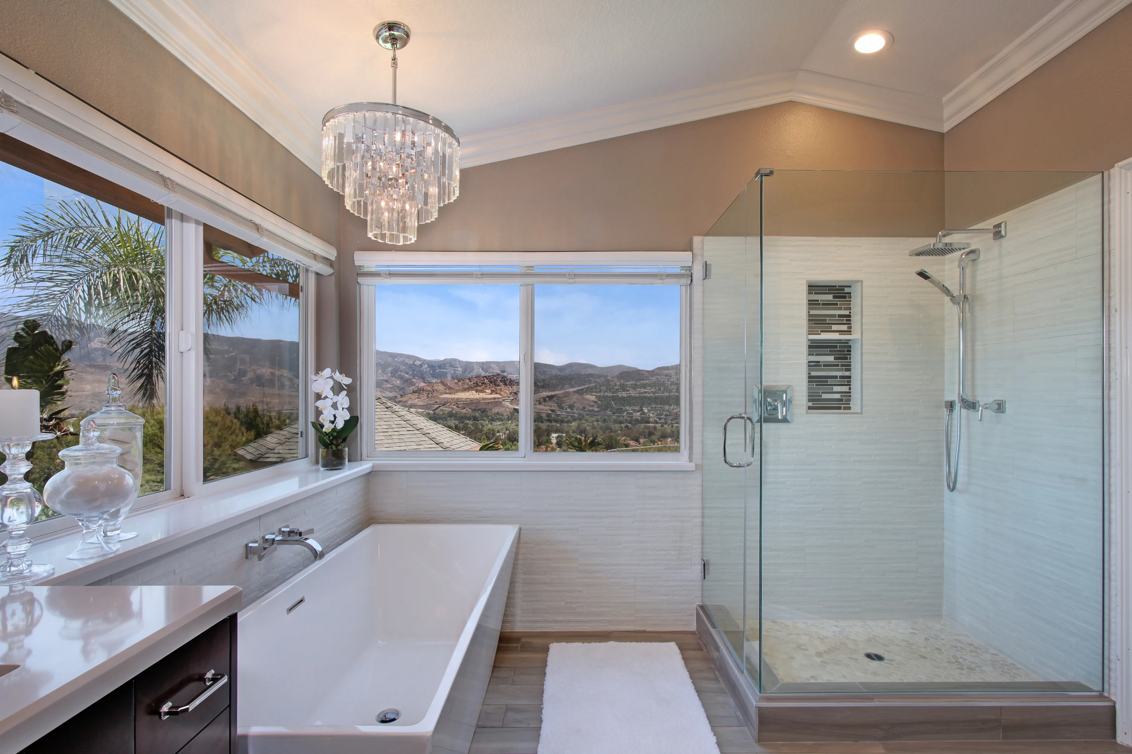 Master bathroom with freestanding tub, glass shower, and wide valley view