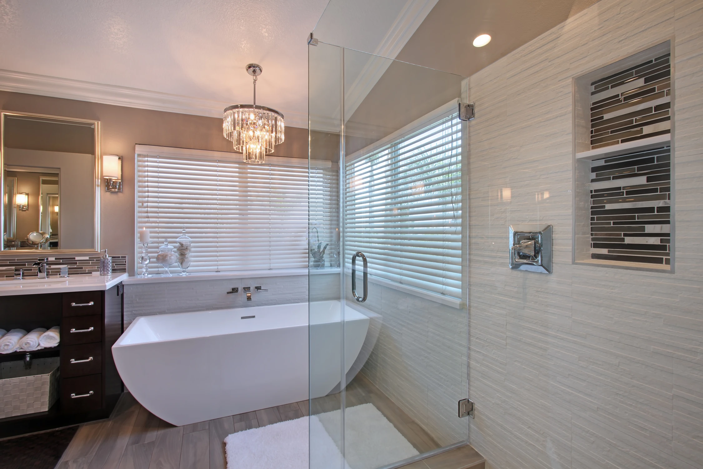 Master bathroom tub and glass shower beneath a crystal chandelier