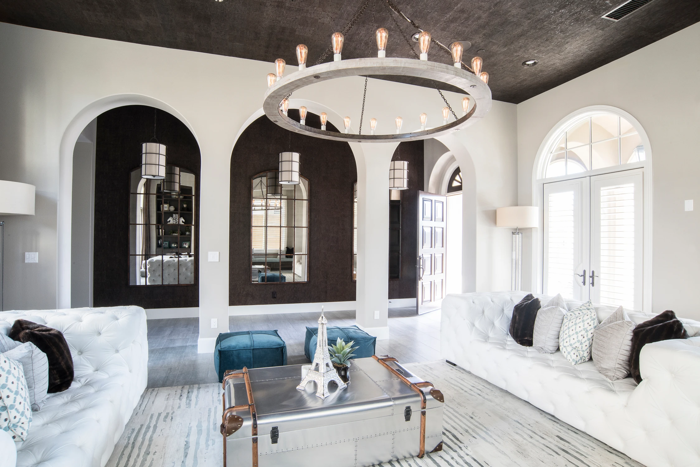 Formal living room with white tufted sofa, arches, and blue ottoman