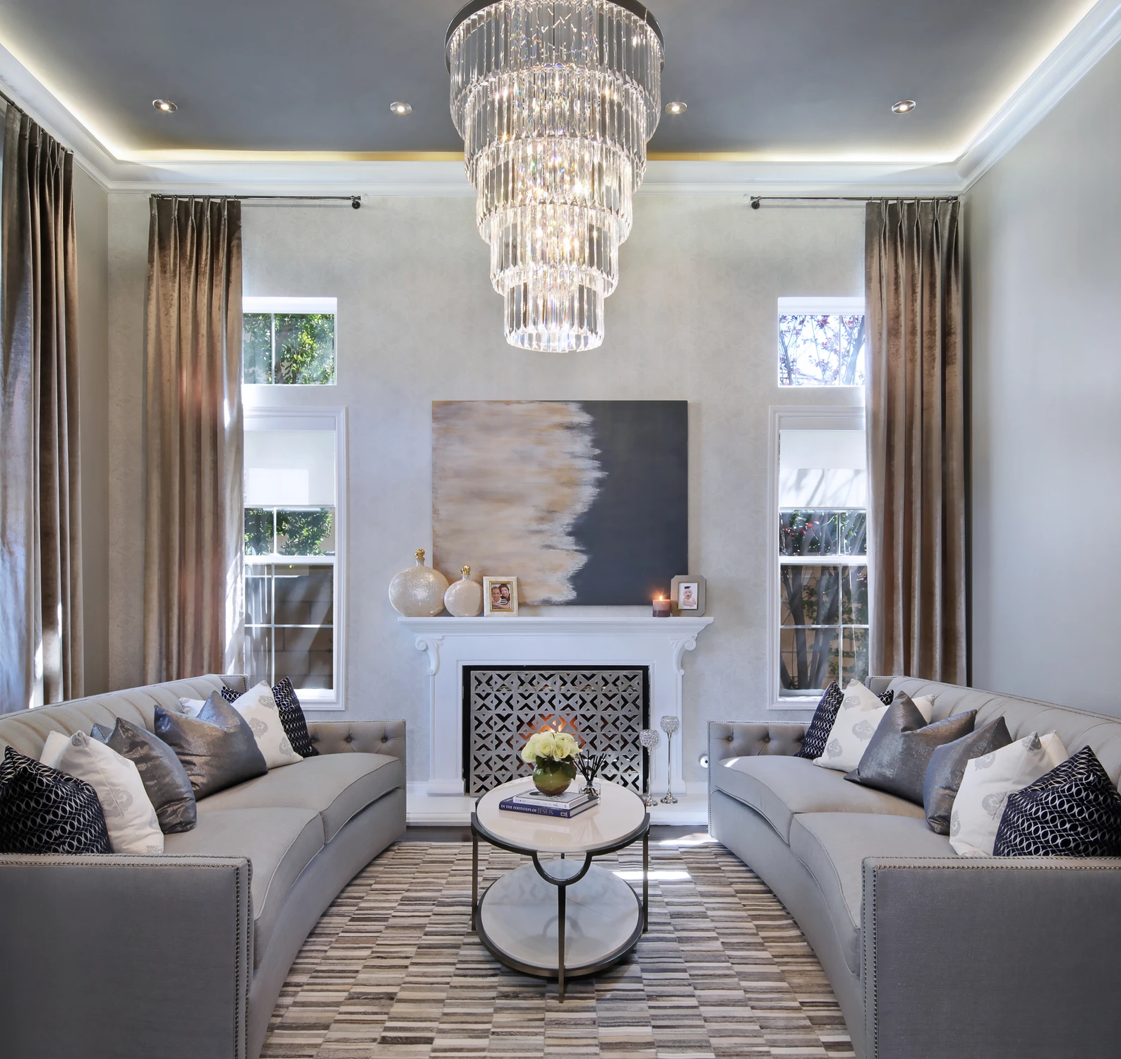 Living room with crystal chandelier, white sofas, and fireplace