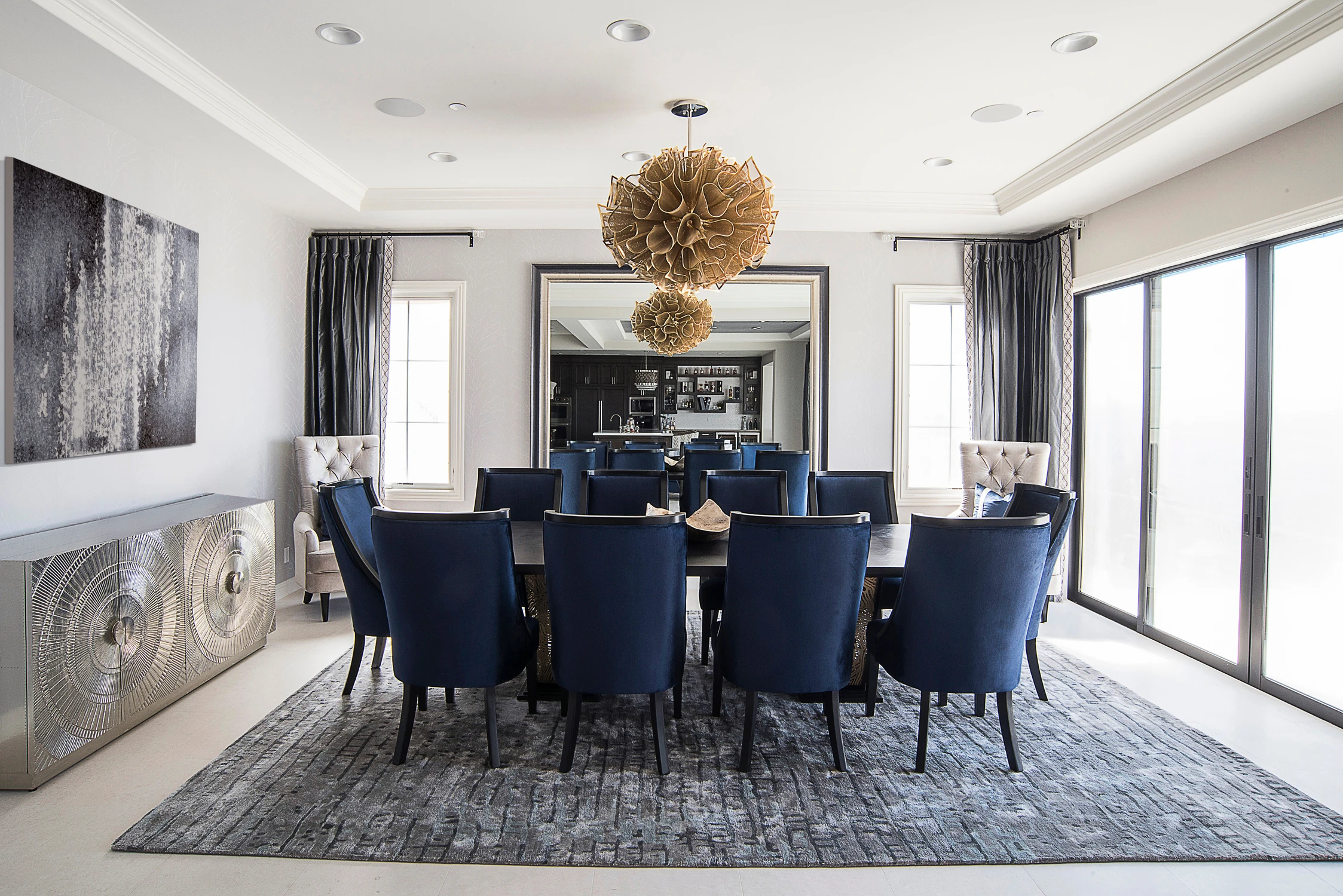 Formal dining room with navy chairs and sculptural chandelier