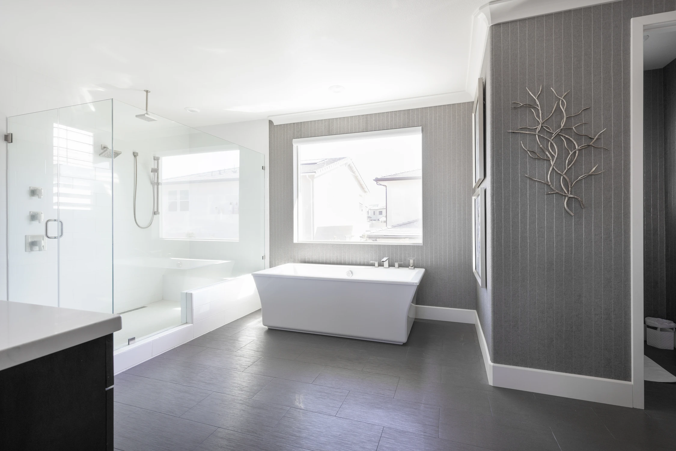 Master bathroom with glass shower, freestanding tub, and dark floor tile