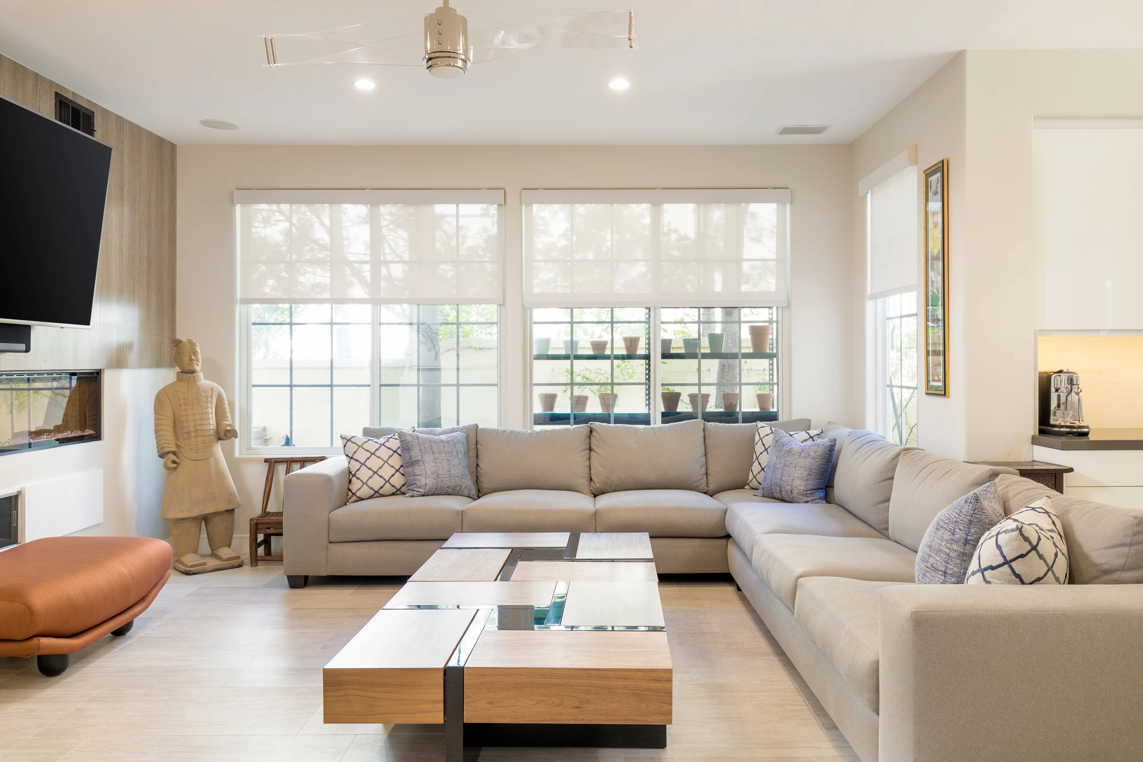 Bright living room with sectional sofa, pale wood floor, and wide windows