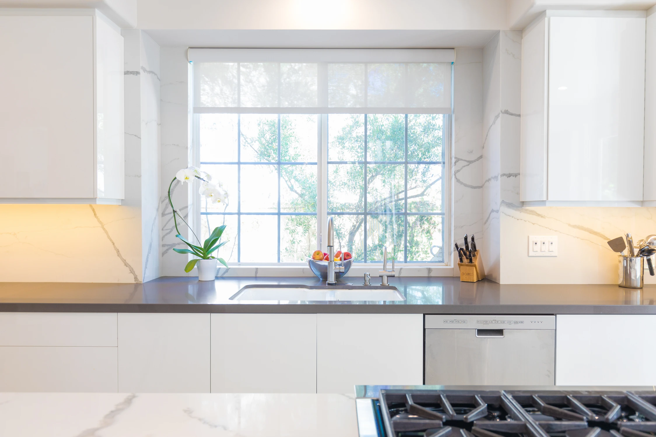 Kitchen window and stainless sink above dark countertop
