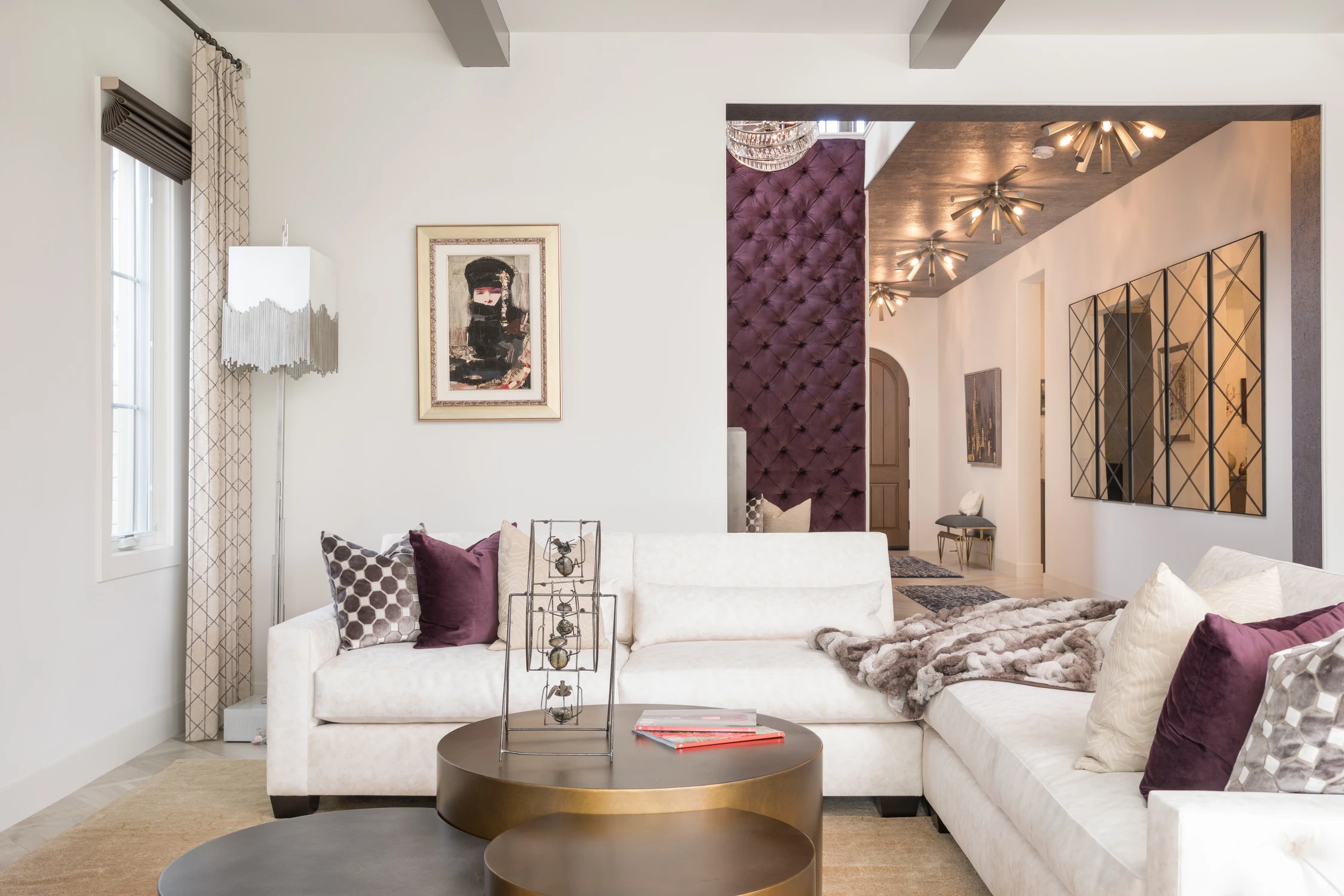 White sectional with plum pillows and mirrored wall panels