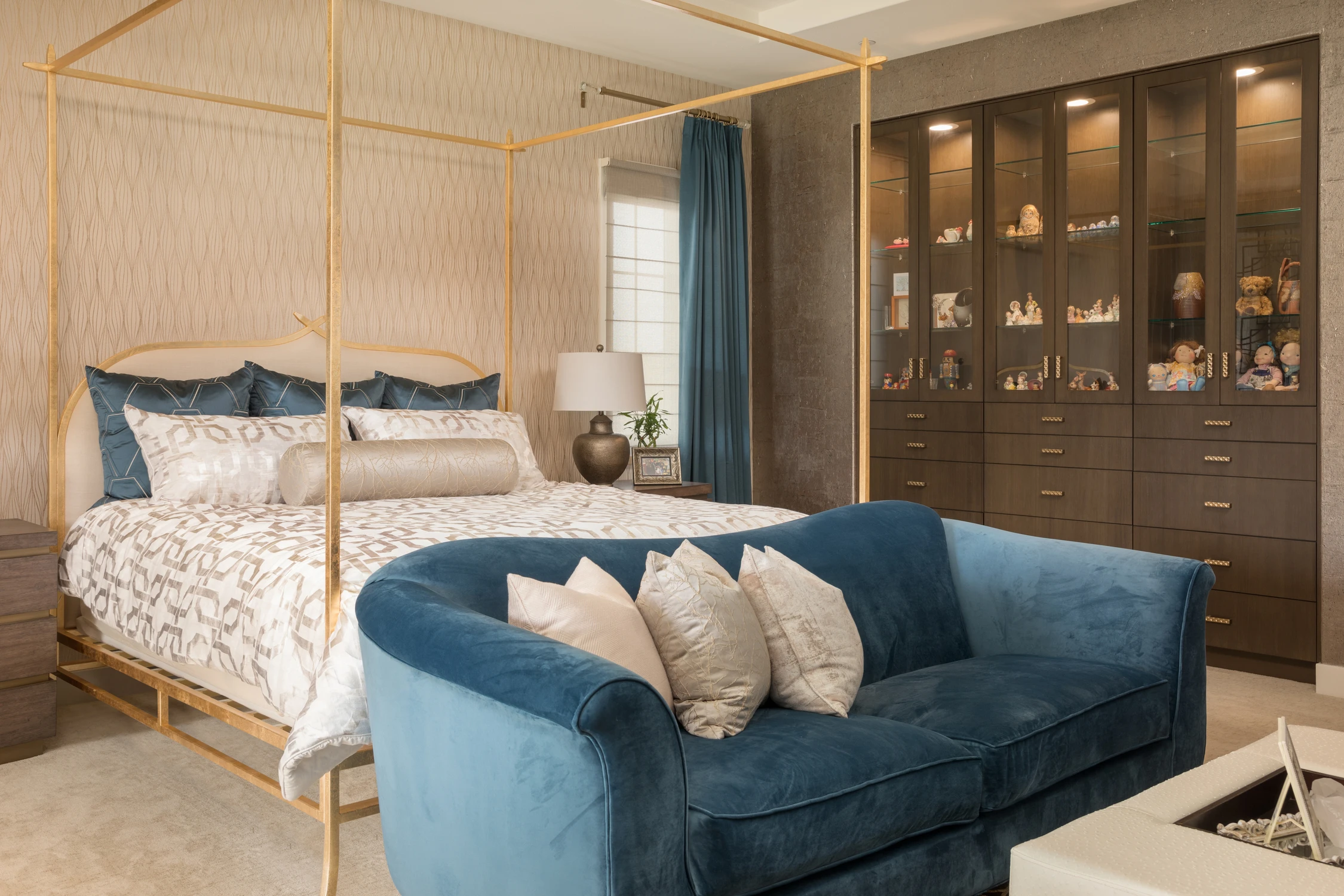 Bedroom with canopy bed, blue velvet sofa, and dark built-in cabinet