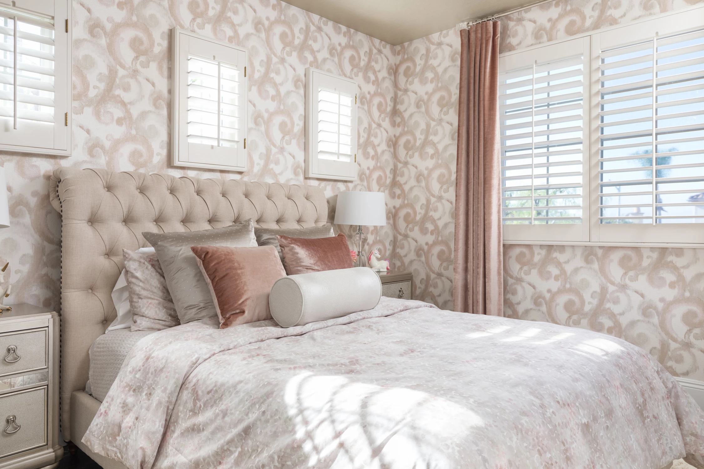 Bedroom with tufted bed, floral wallpaper, and pink drapery