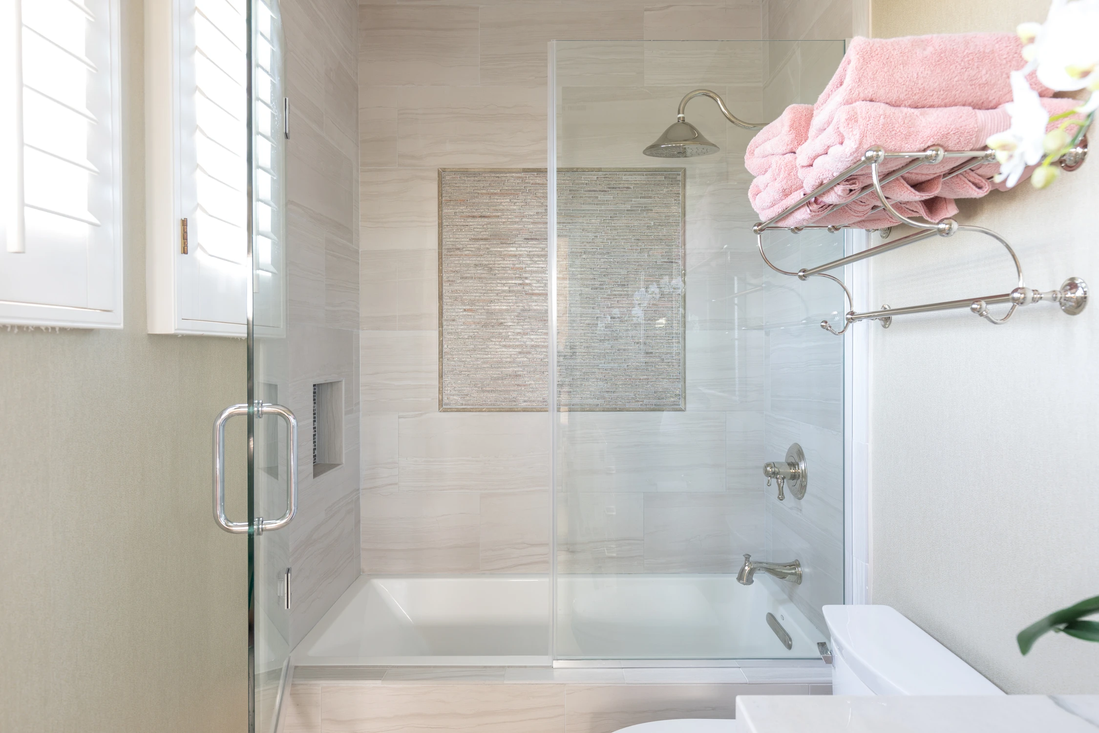 Glass shower and freestanding tub in pale marble bathroom