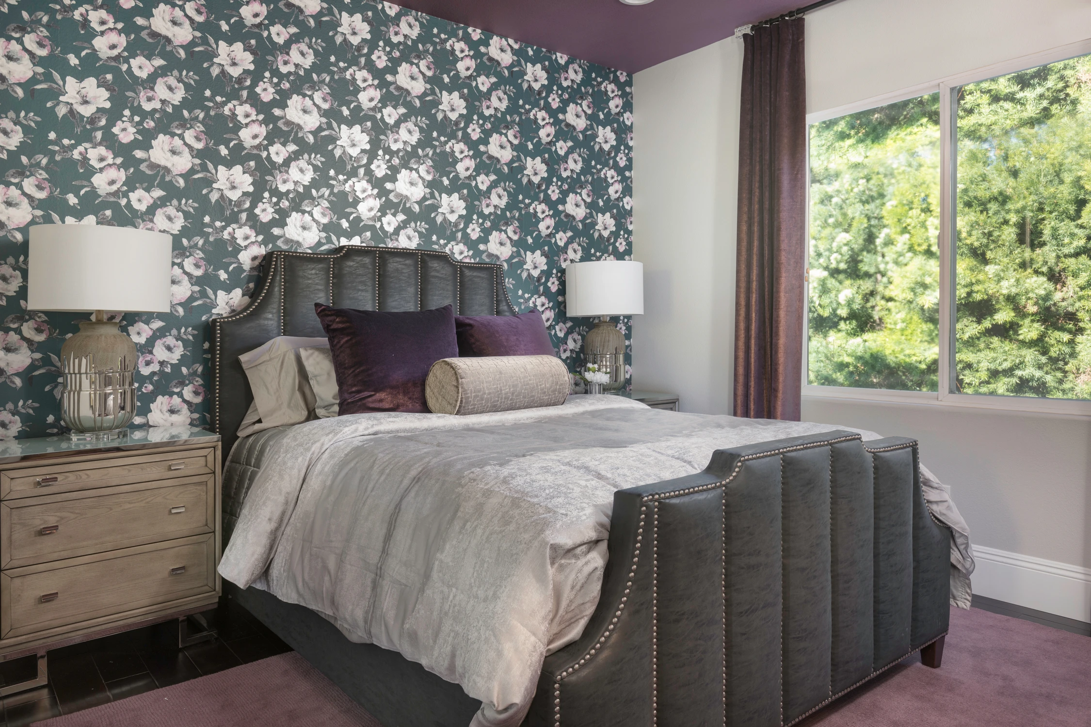 Bedroom with floral wallpaper, gray bed, and garden view
