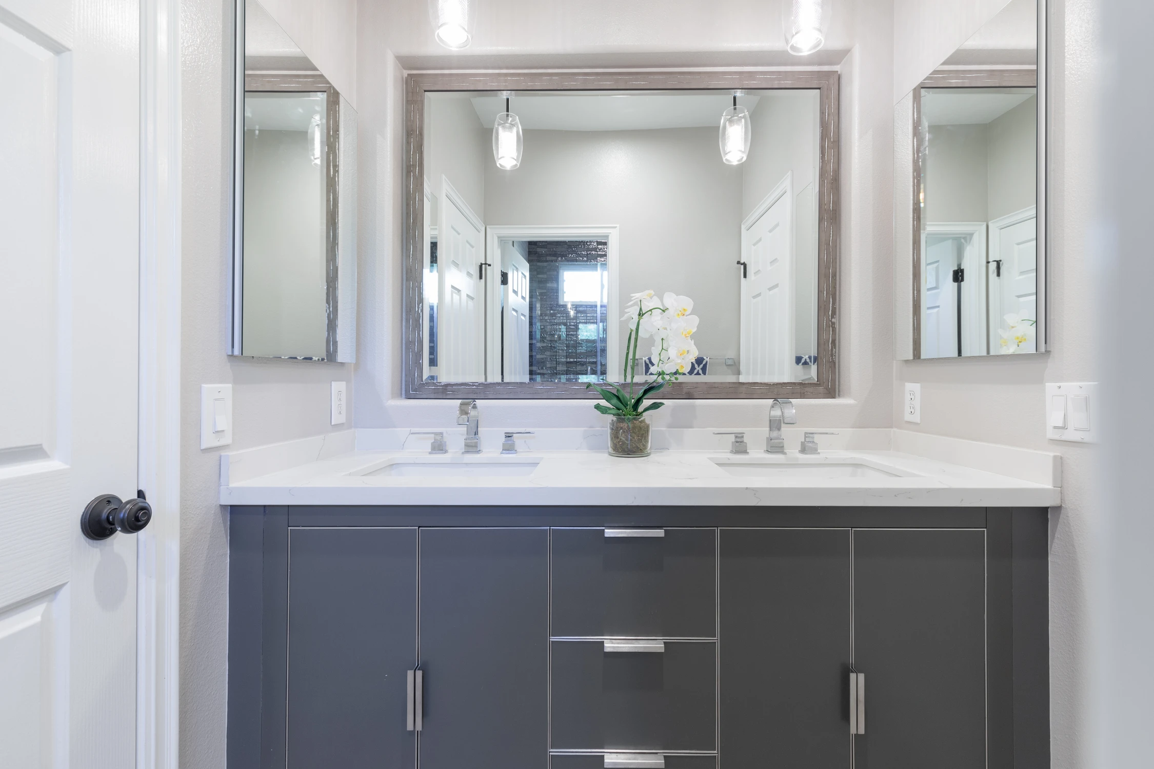 Dark gray bathroom vanity beneath double mirrors