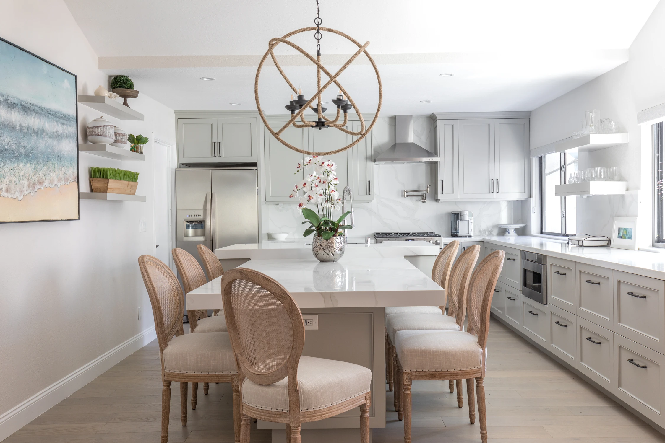 Bright white kitchen and dining room with globe chandelier and pale wood chairs