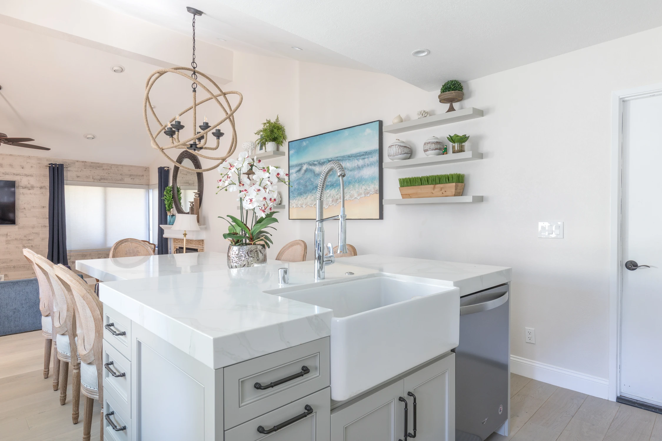 Kitchen island with white counter, pale gray cabinetry, and dining view