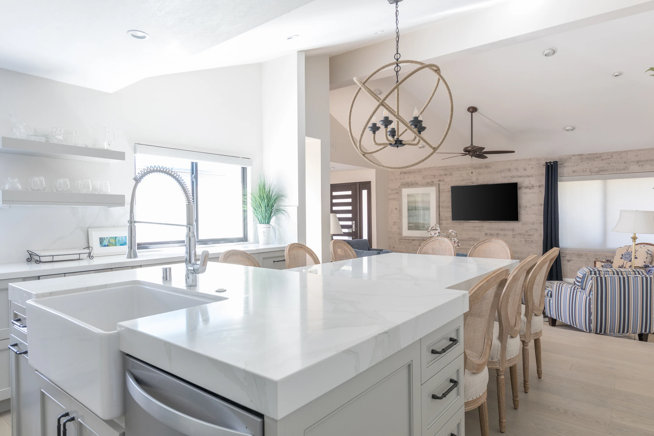 Kitchen island with gooseneck faucet, white counter, and open living room