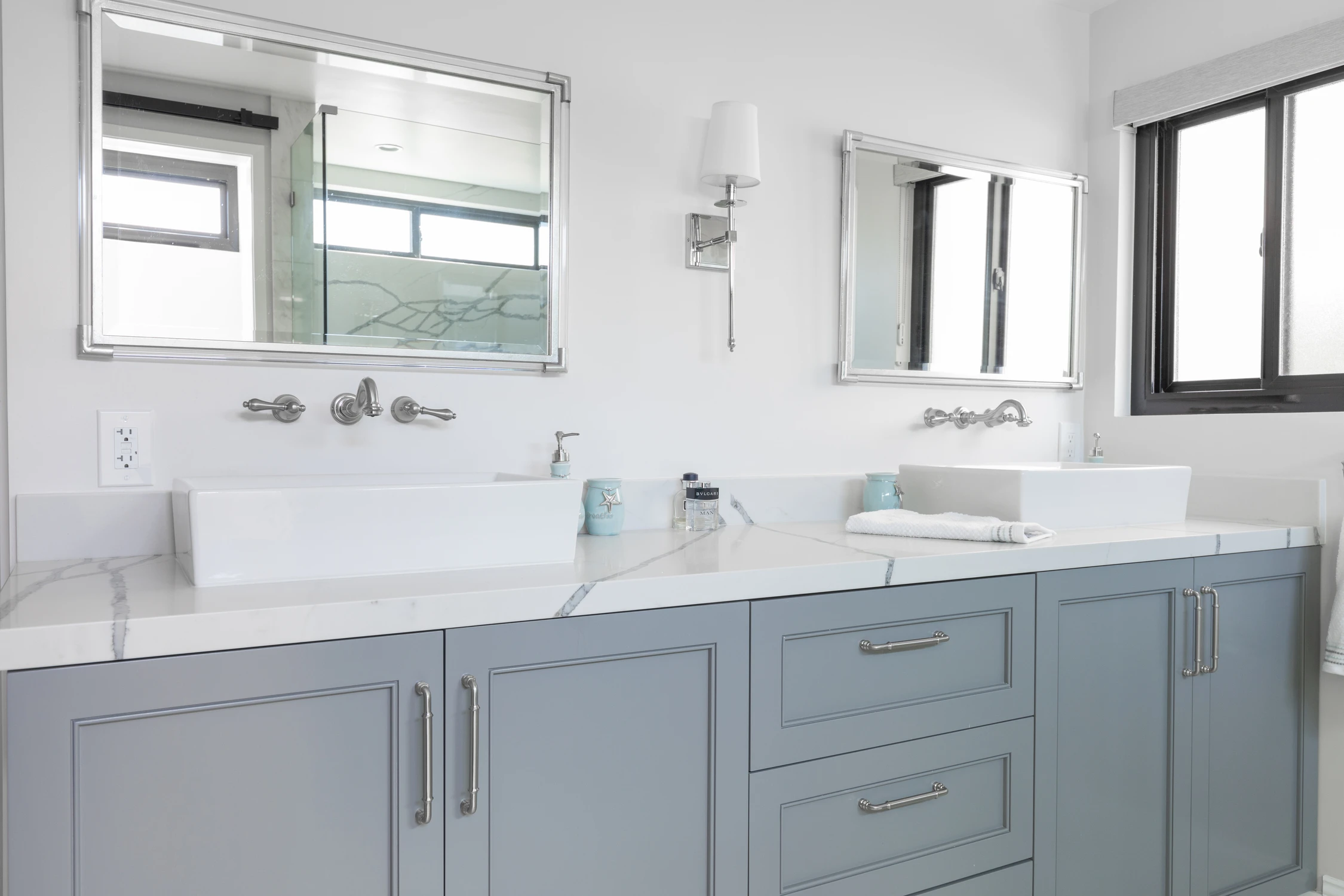 Bathroom double vanity with pale gray drawers and framed mirrors