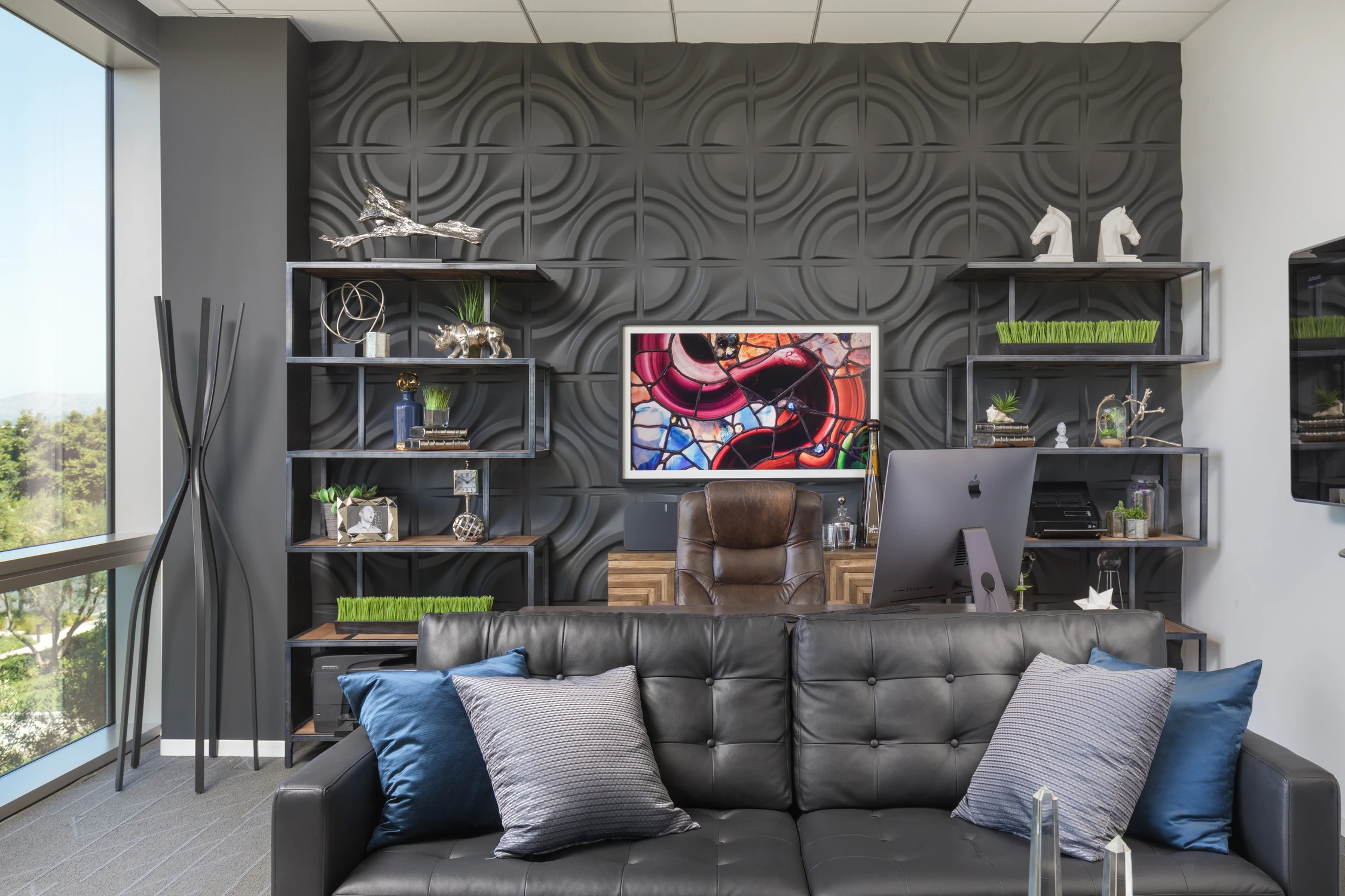 Office lounge with black geometric wall, sofa, and executive desk
