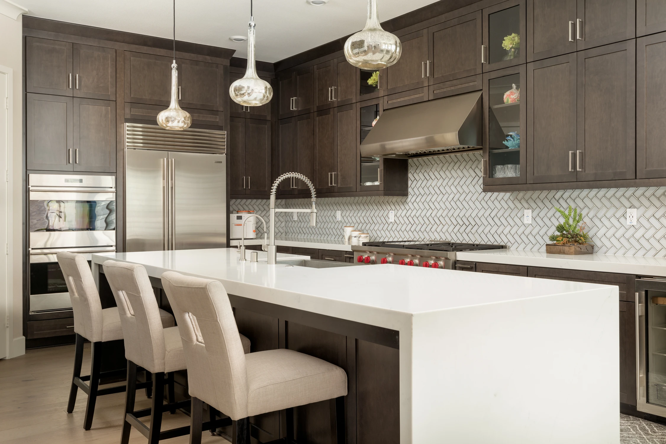 Kitchen island with upholstered stools beneath glass pendant lights