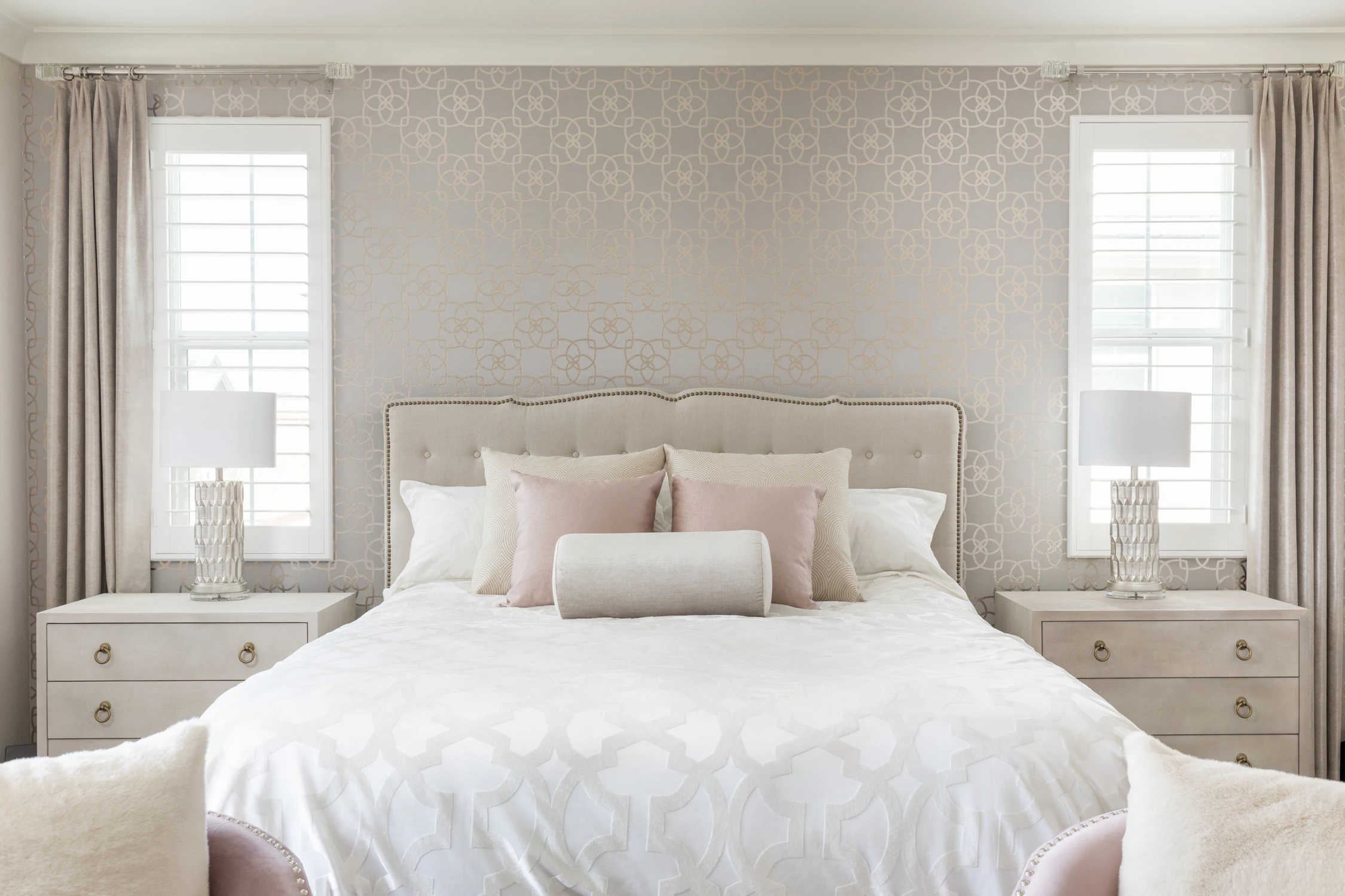 Bedroom with white bedding, pale nightstands, and textured feature wall