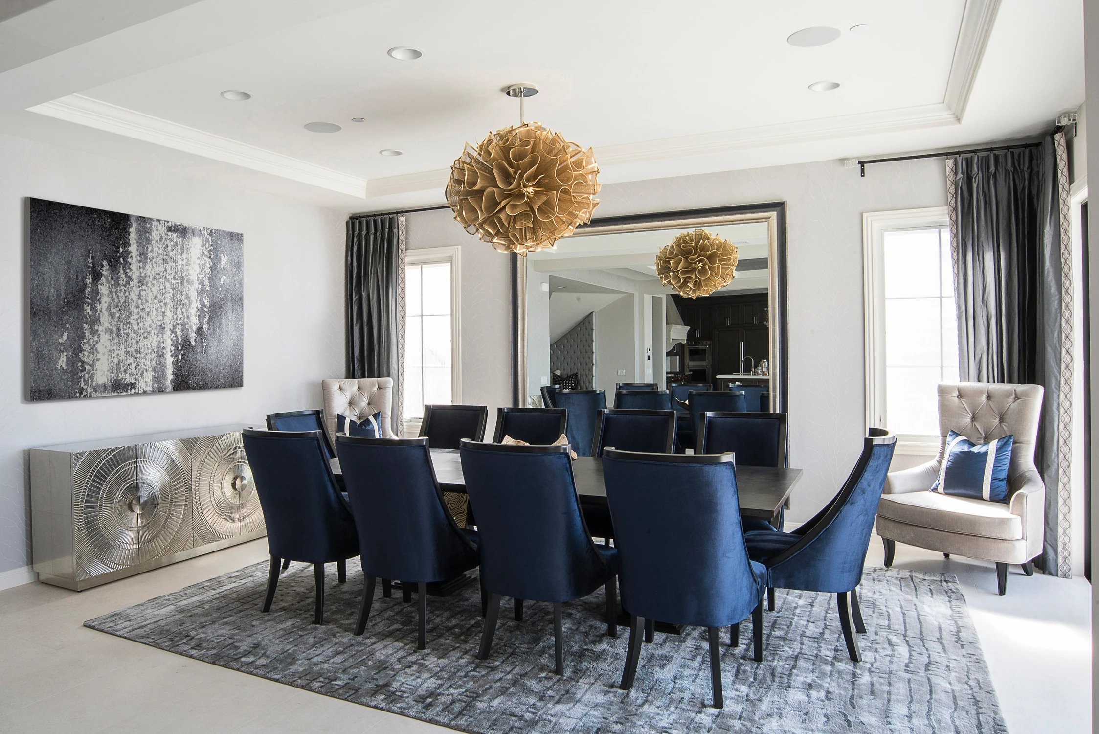 Formal dining room with navy chairs, mirror, and sculptural chandelier