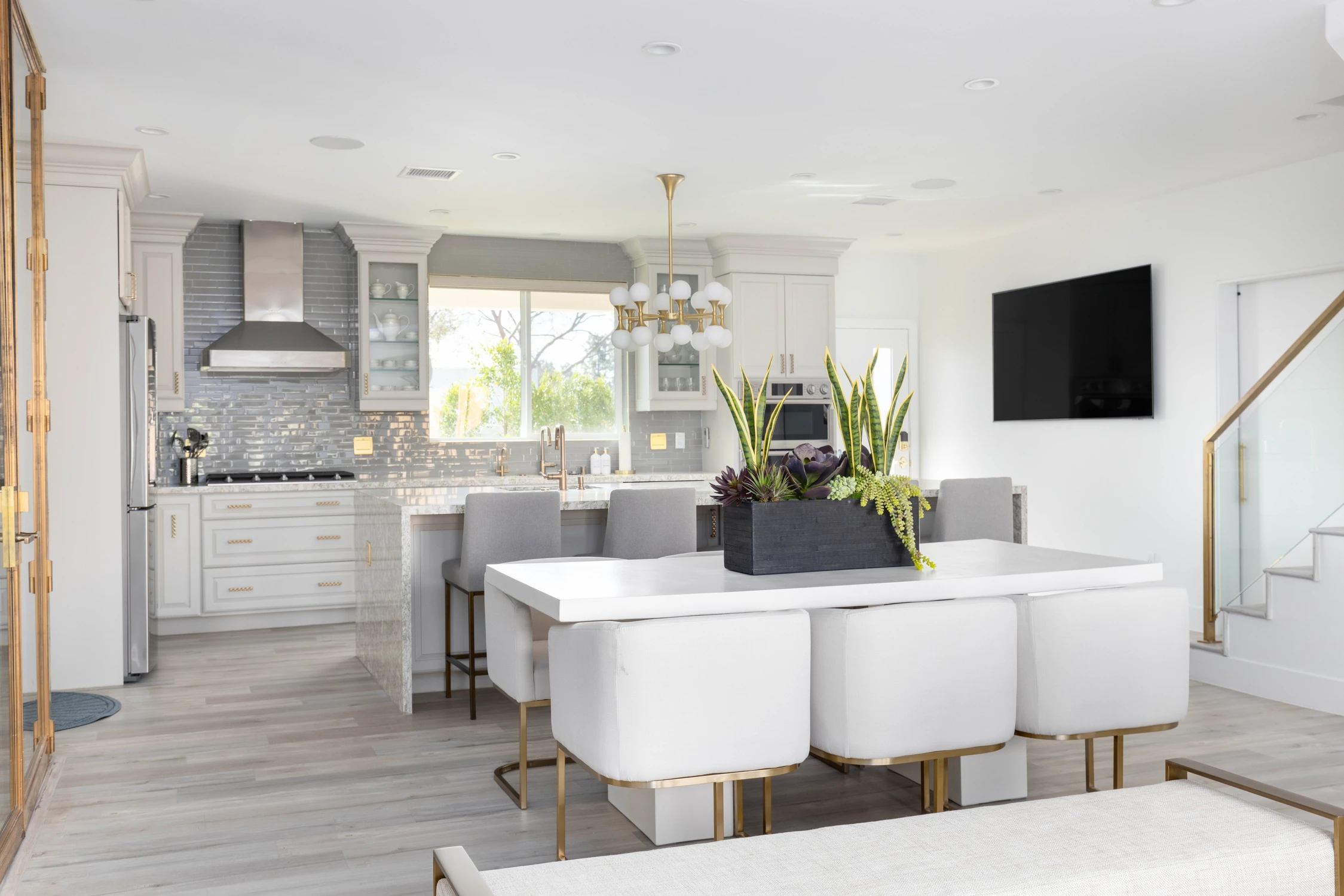 Open kitchen with warm beige island cabinetry, pale stools, and adjoining living room