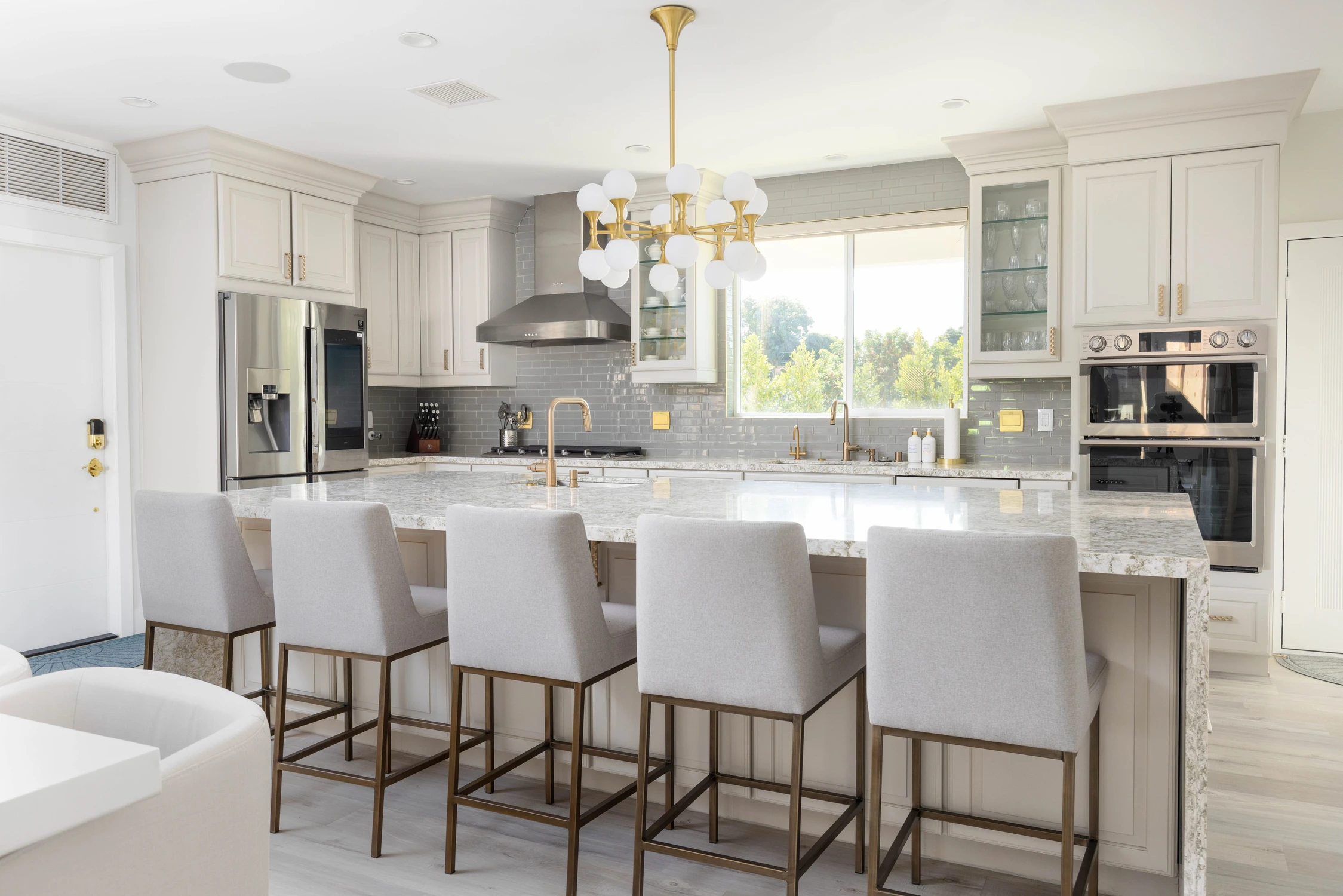 Warm beige kitchen with island seating and gold chandelier