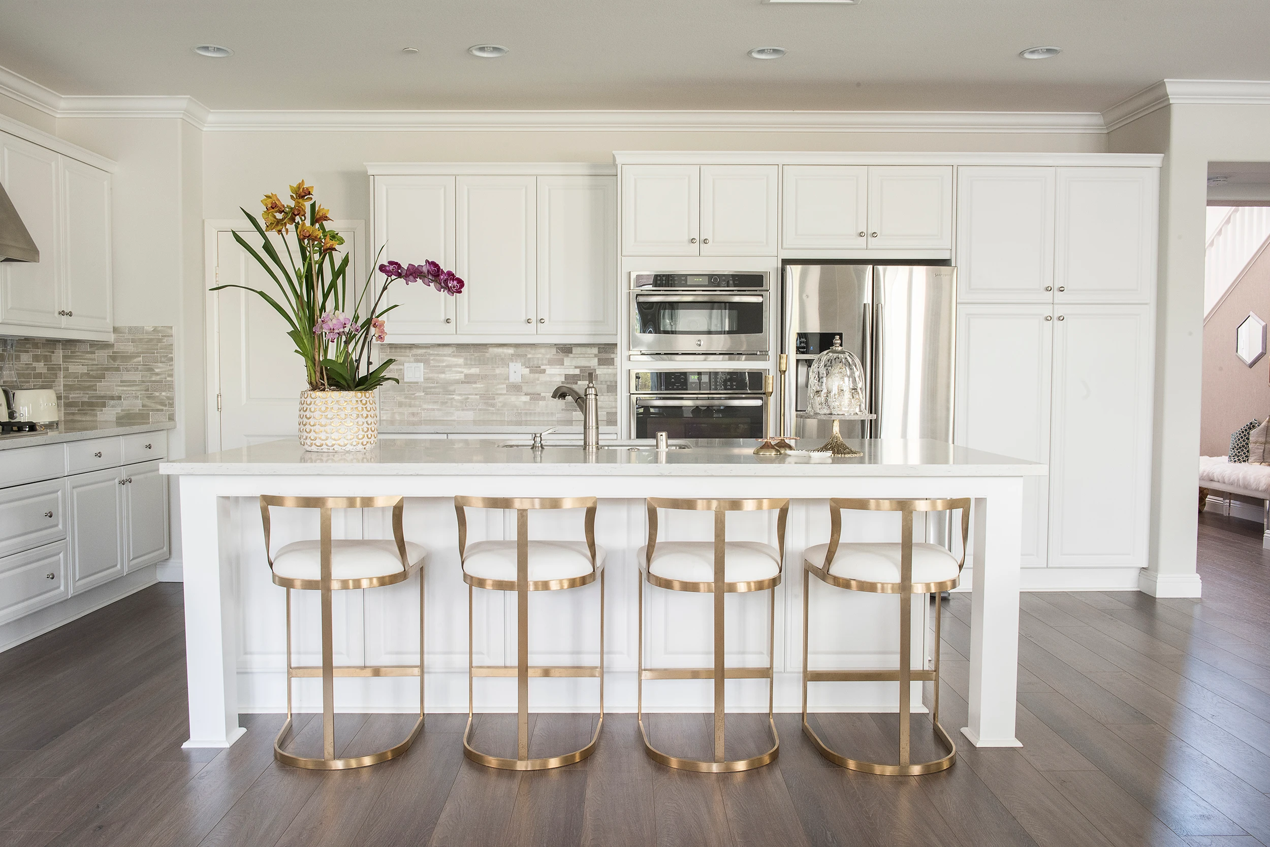 Kitchen island with orchids and four gold-framed stools