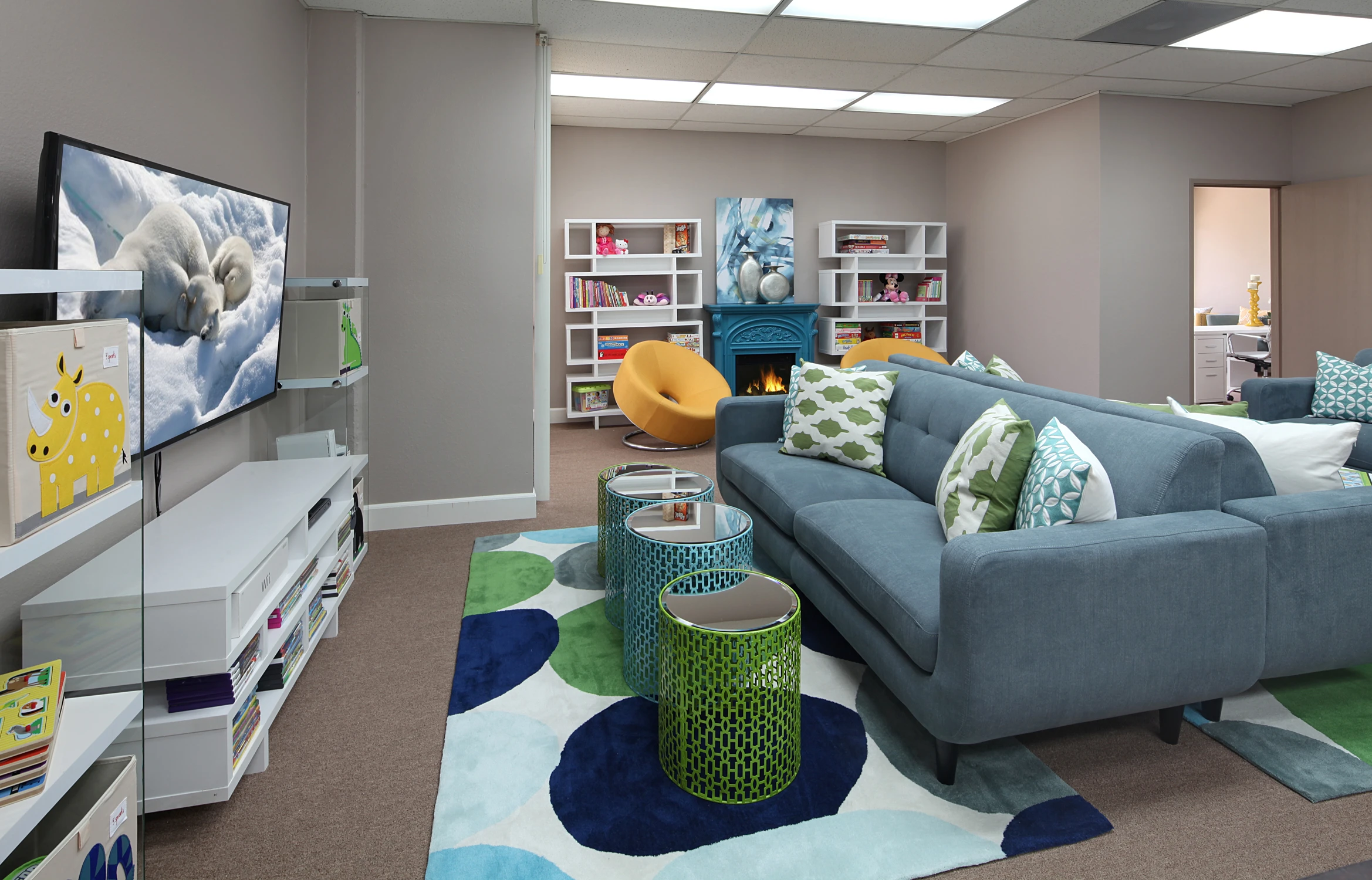 Children's game room with blue sectional, colorful rug, and play area
