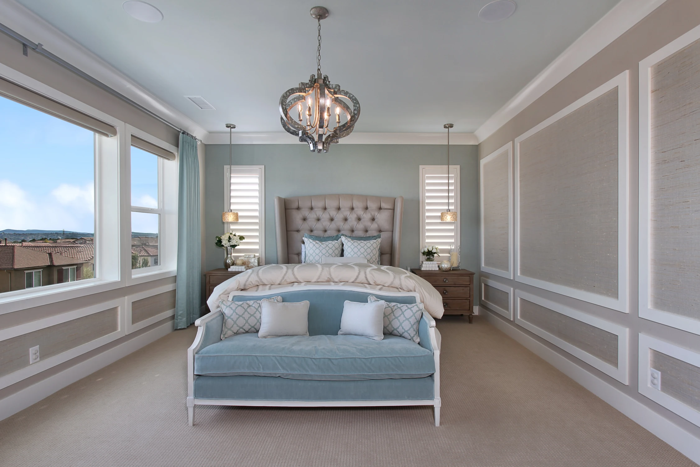 Master bedroom with tall tufted headboard, blue bench, and scenic windows
