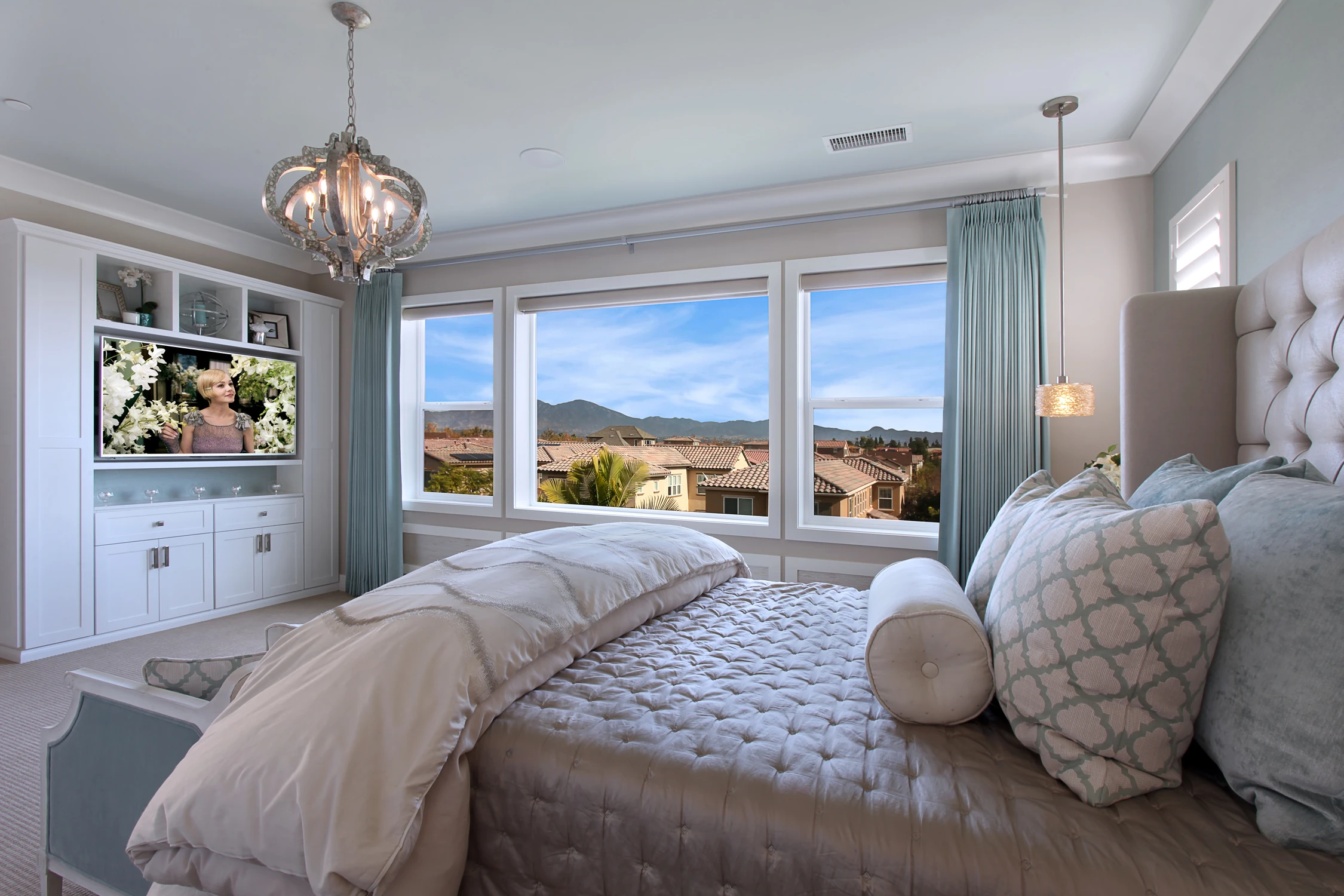 Master bedroom with upholstered bed, built-in media wall, and wide windows