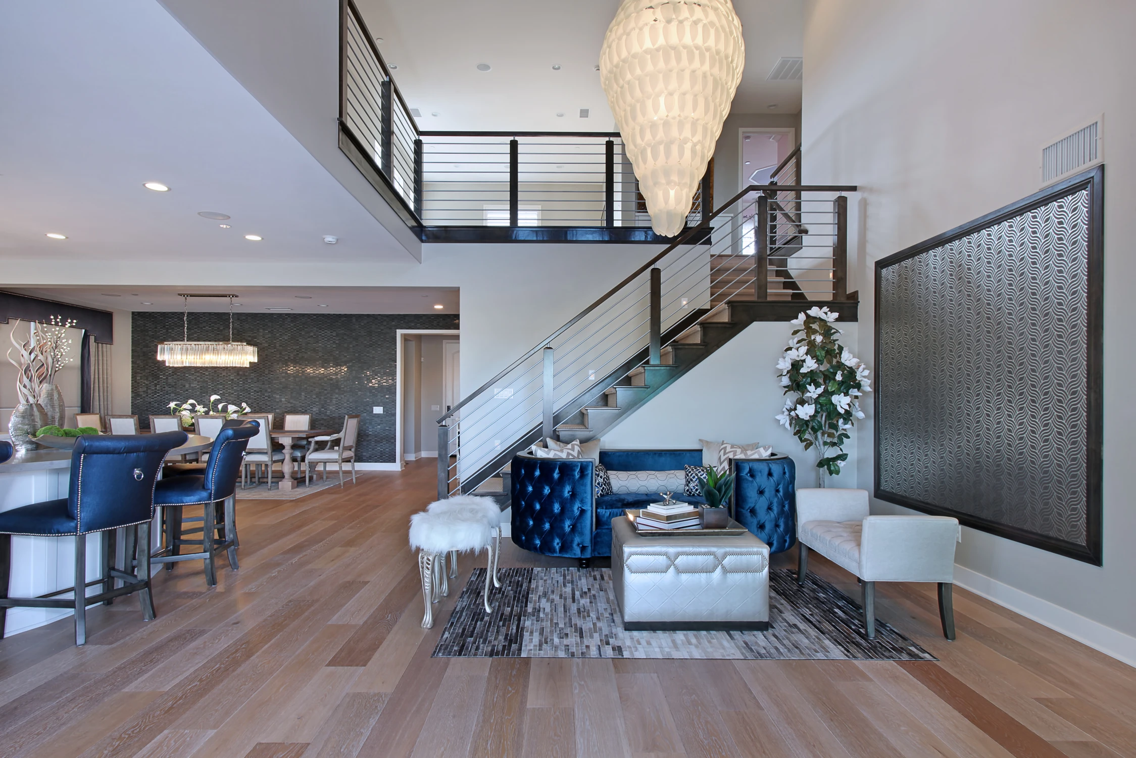 Great room with blue bar stools, wide kitchen island, and open staircase