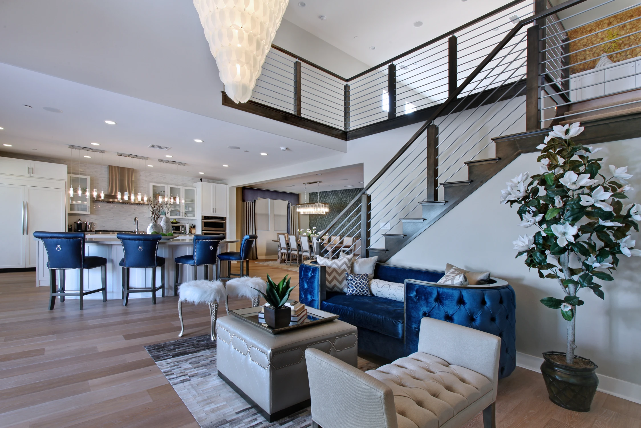 Open great room with white dining table, blue seating, and glass doors